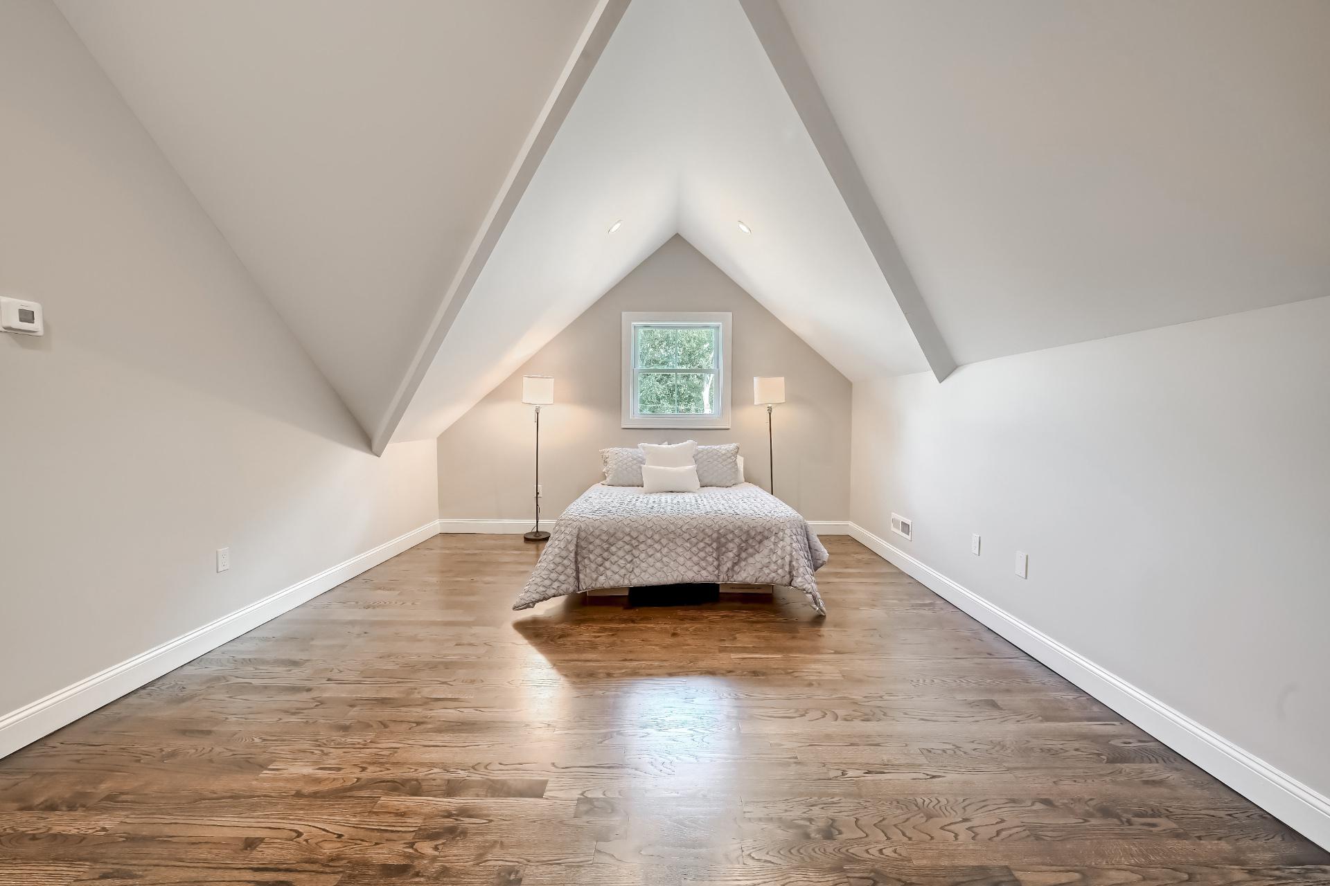 There is a bed in the attic with a vaulted ceiling.