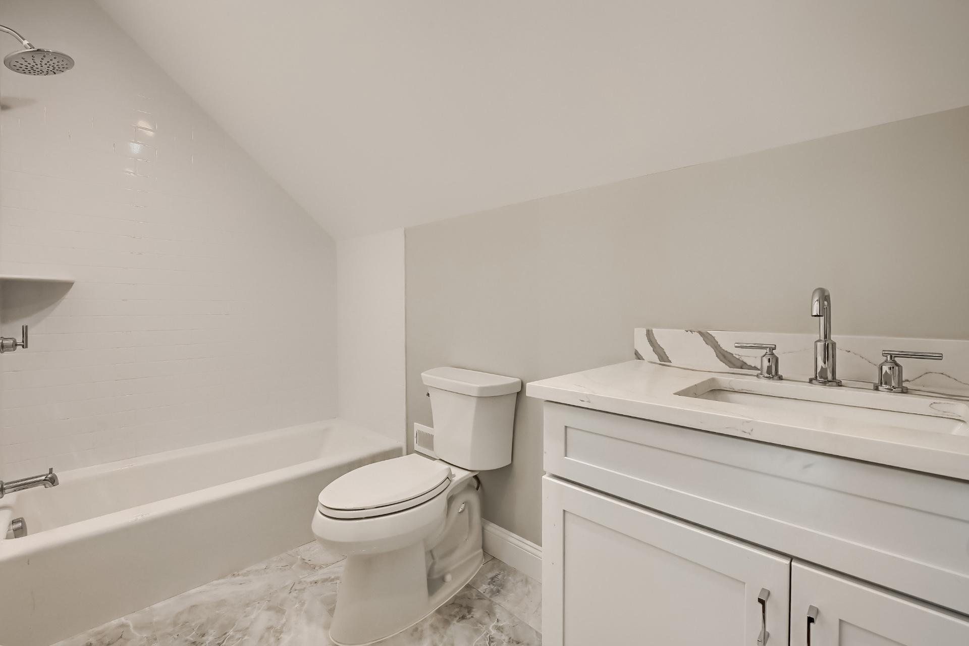 A bathroom with a toilet , sink , bathtub and shower.