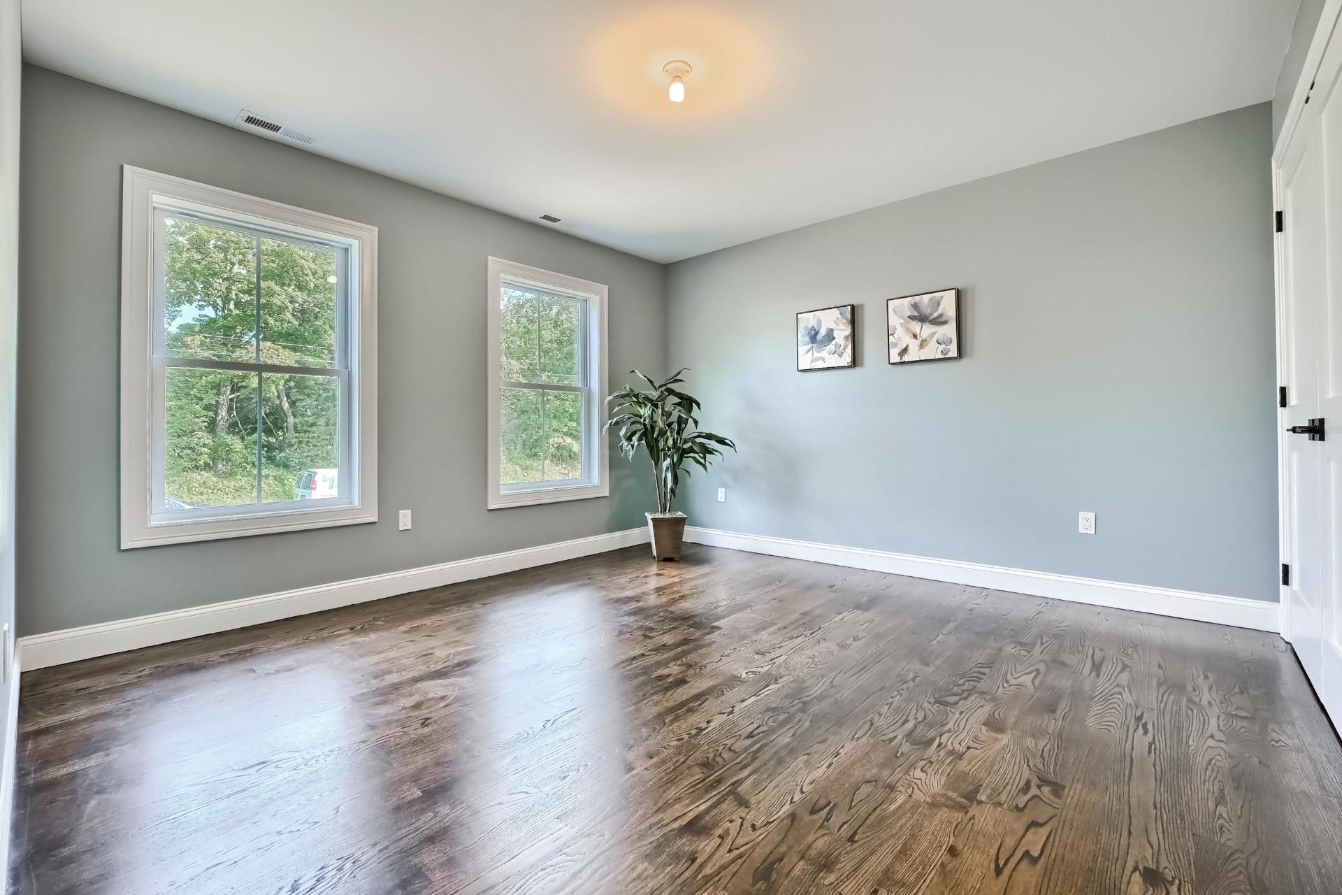 A large empty room with hardwood floors and gray walls.