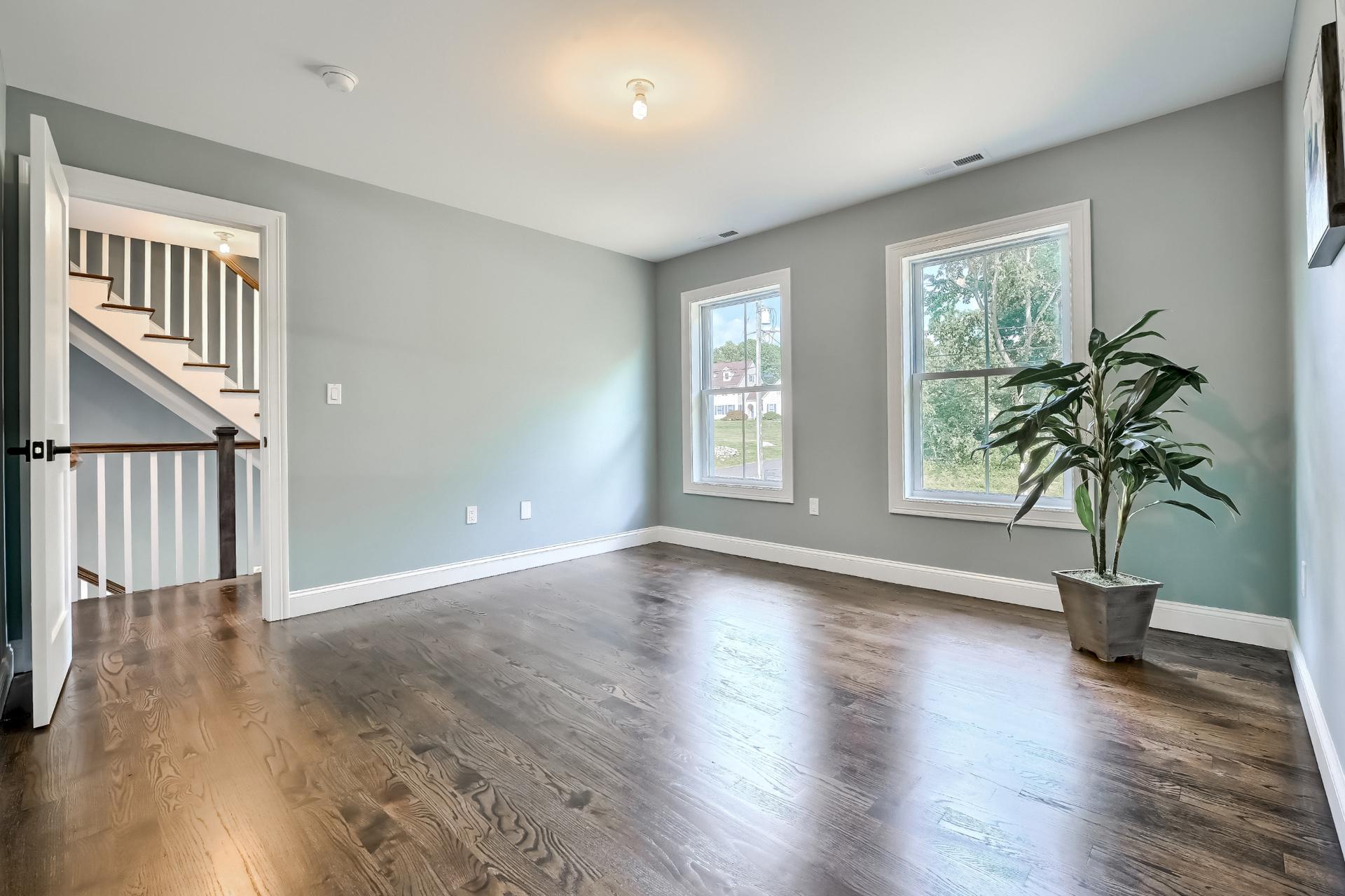 An empty living room with hardwood floors and a potted plant.