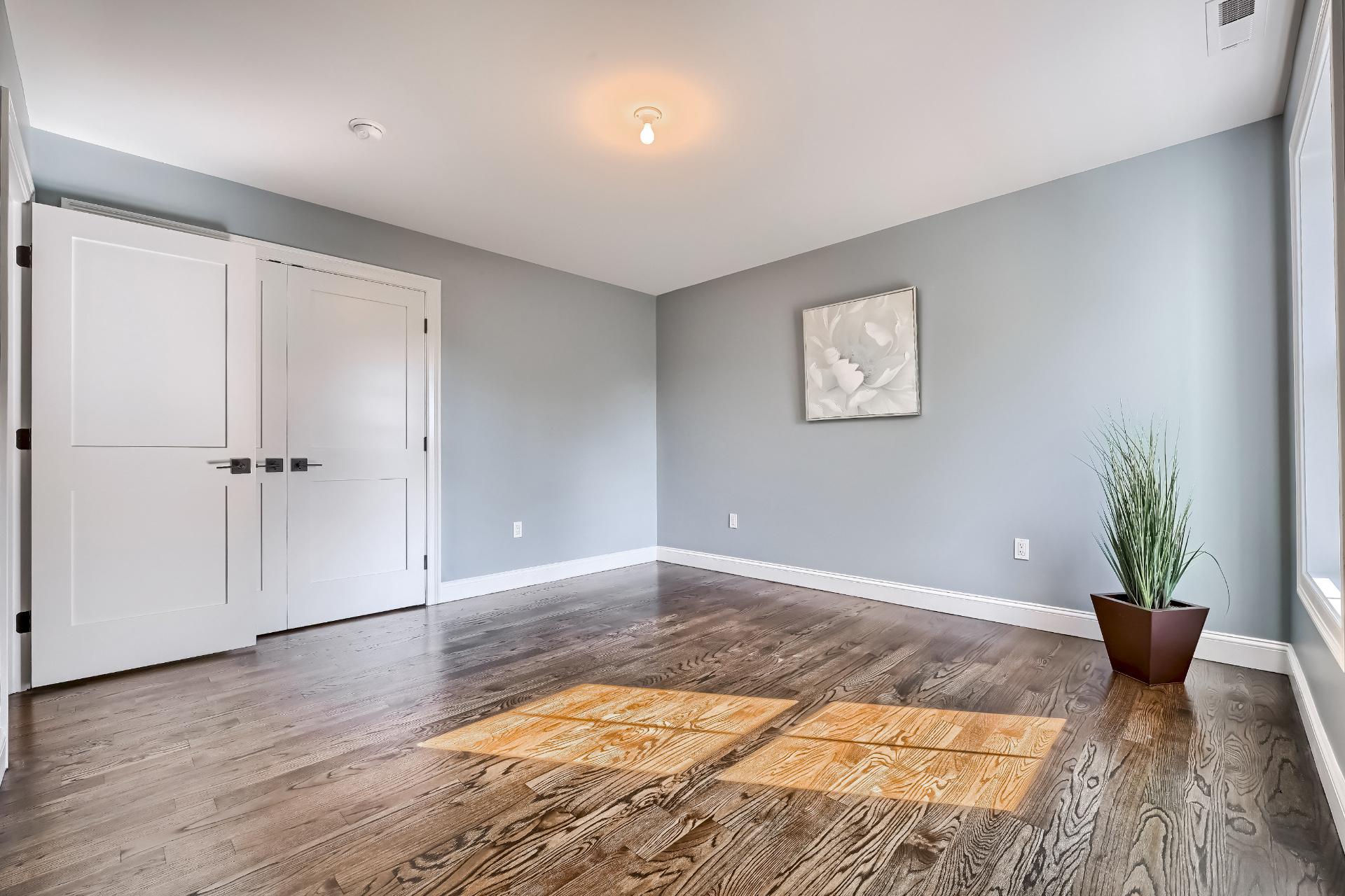 A large empty room with hardwood floors and gray walls.