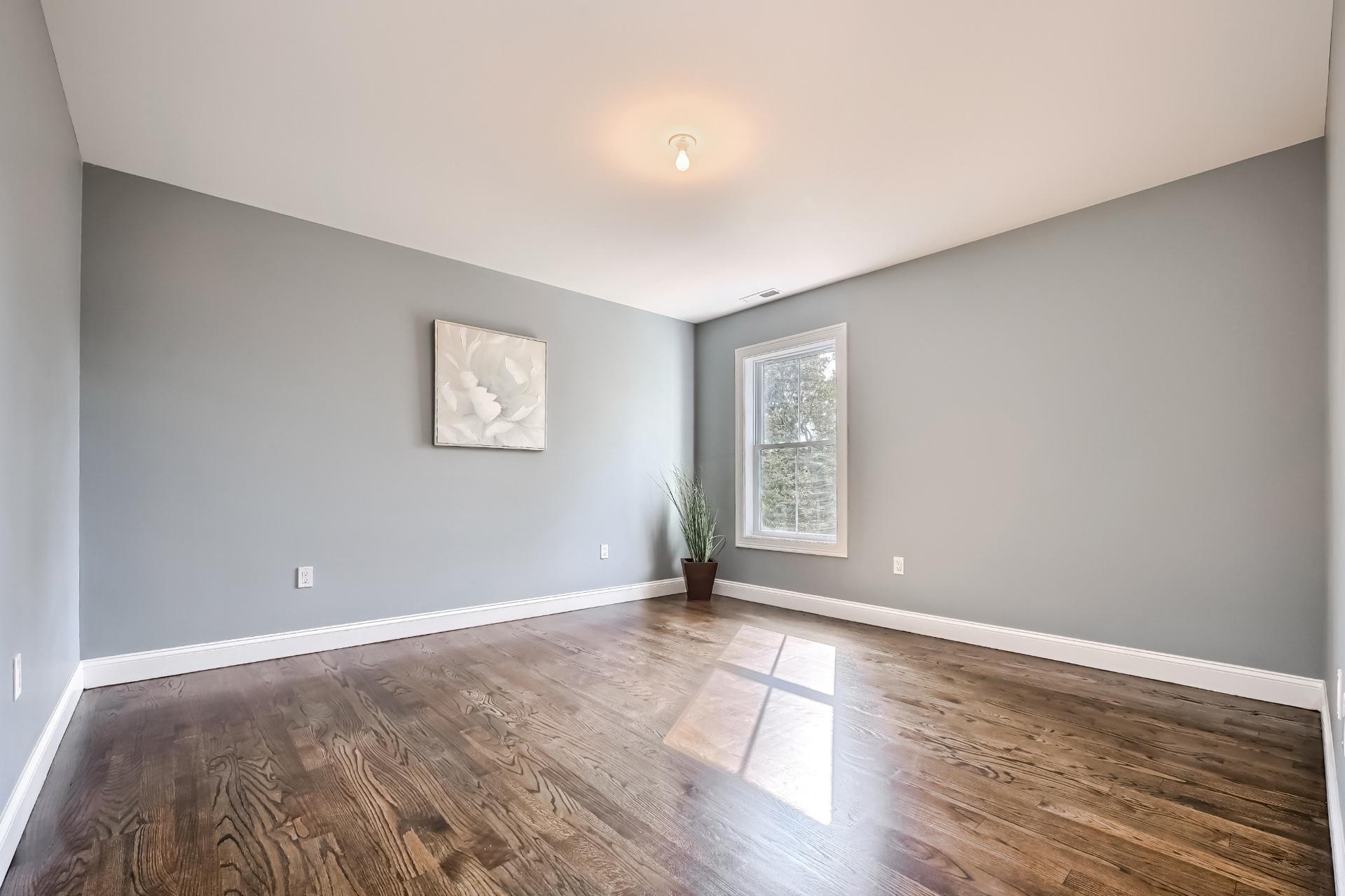 A large empty room with hardwood floors and gray walls.