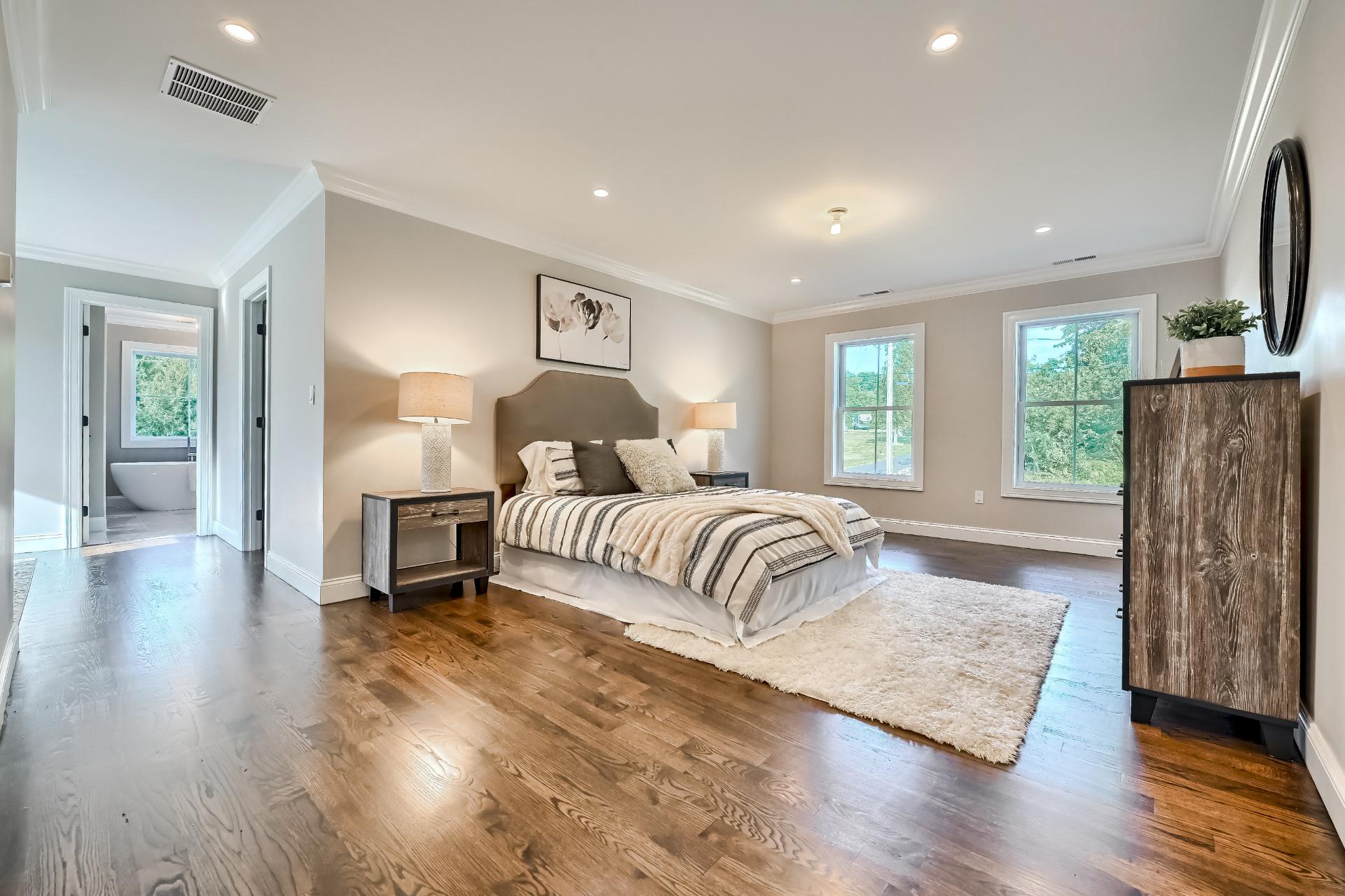 A large bedroom with hardwood floors and a large bed.
