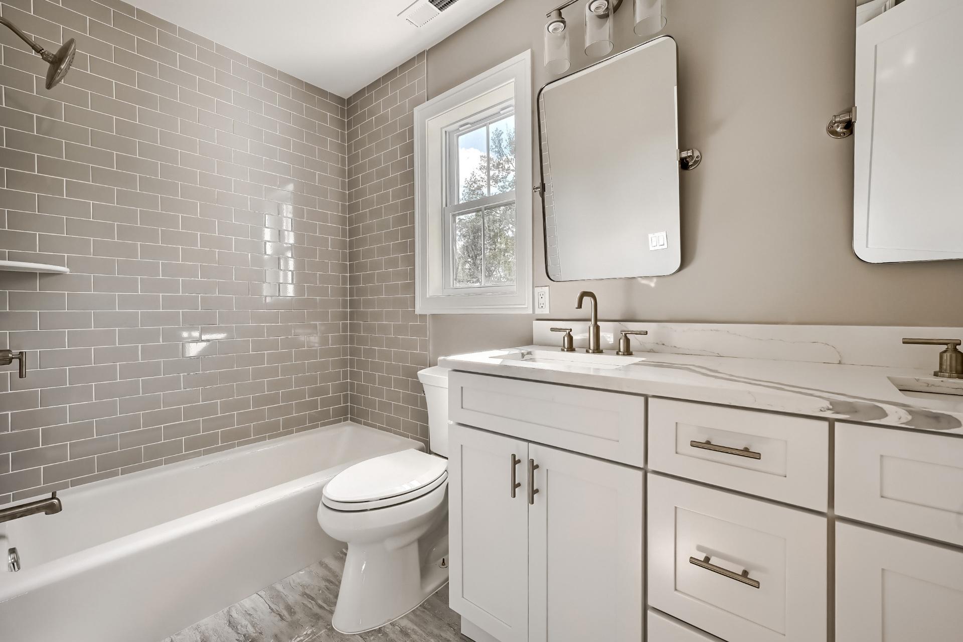 A bathroom with a toilet , sink , tub and mirror.