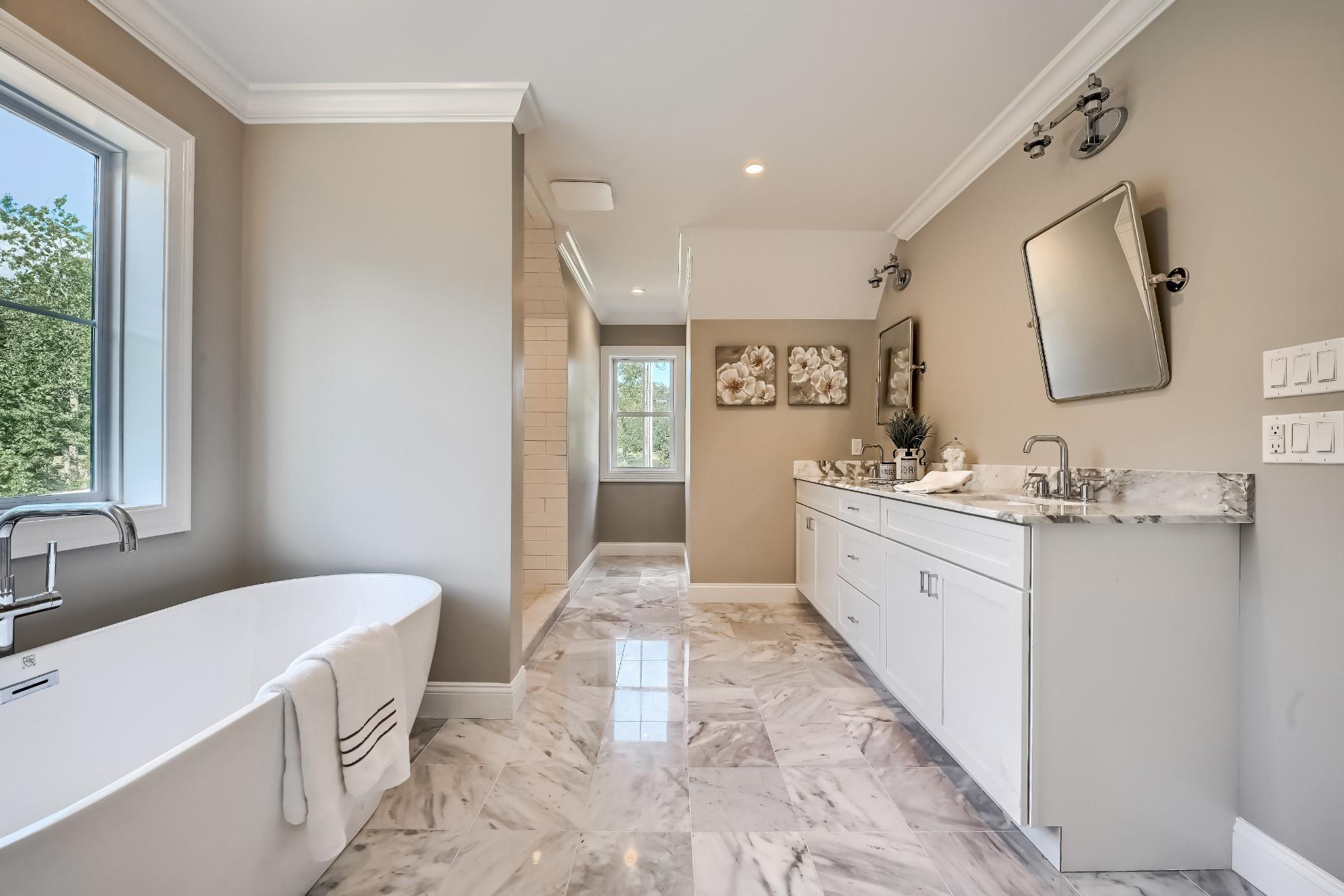 A bathroom with a tub , sink , mirror and window.