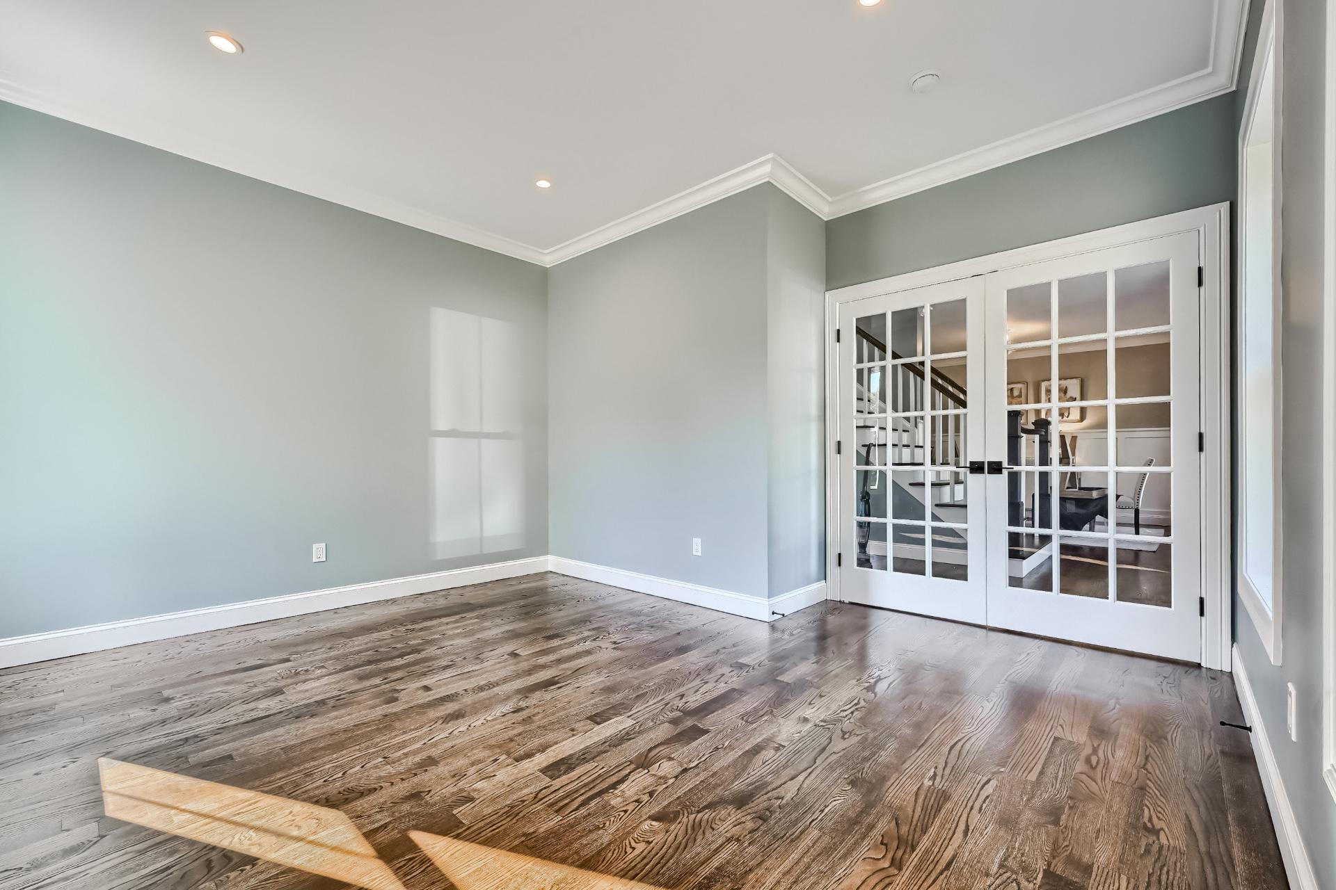 An empty living room with hardwood floors and french doors.