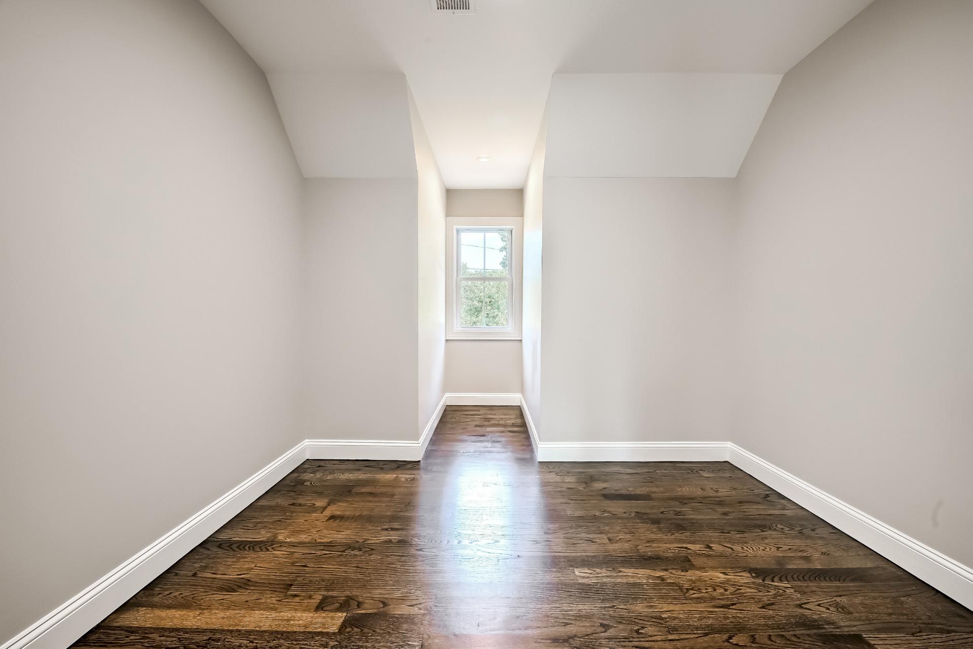 An empty room with hardwood floors and a window.
