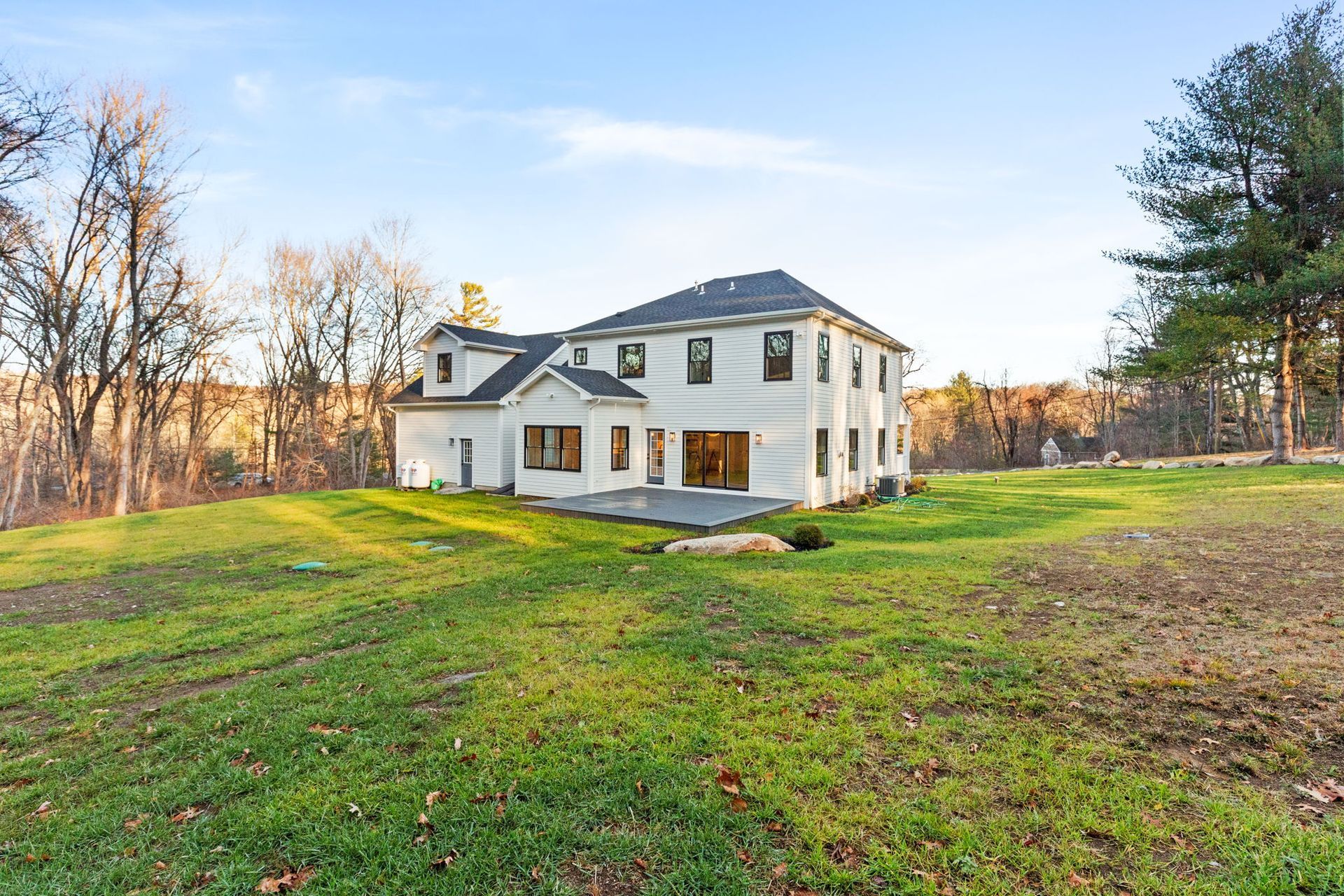 A large white house sits in the middle of a lush green field