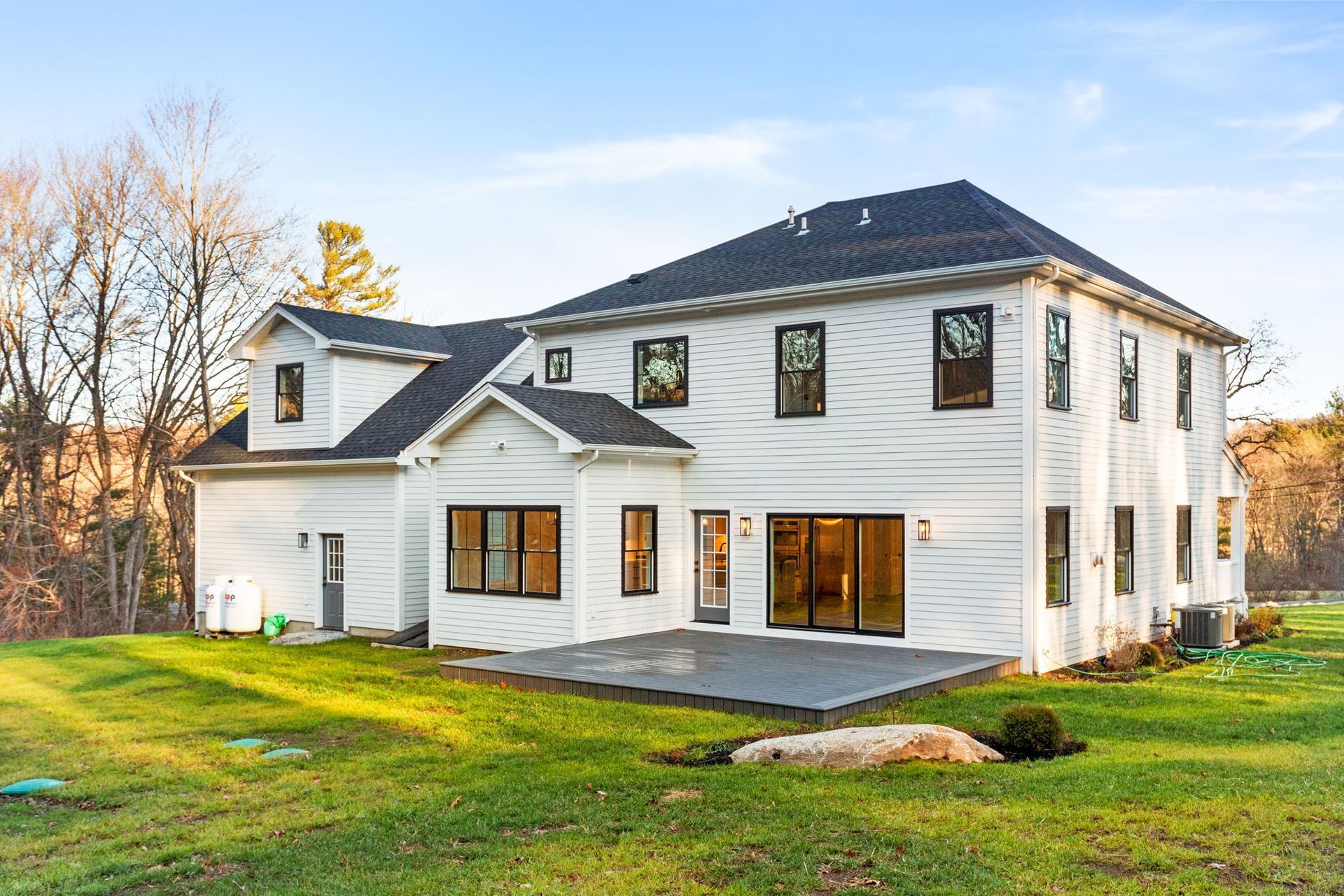 A large white house with a black roof is sitting on top of a lush green field.