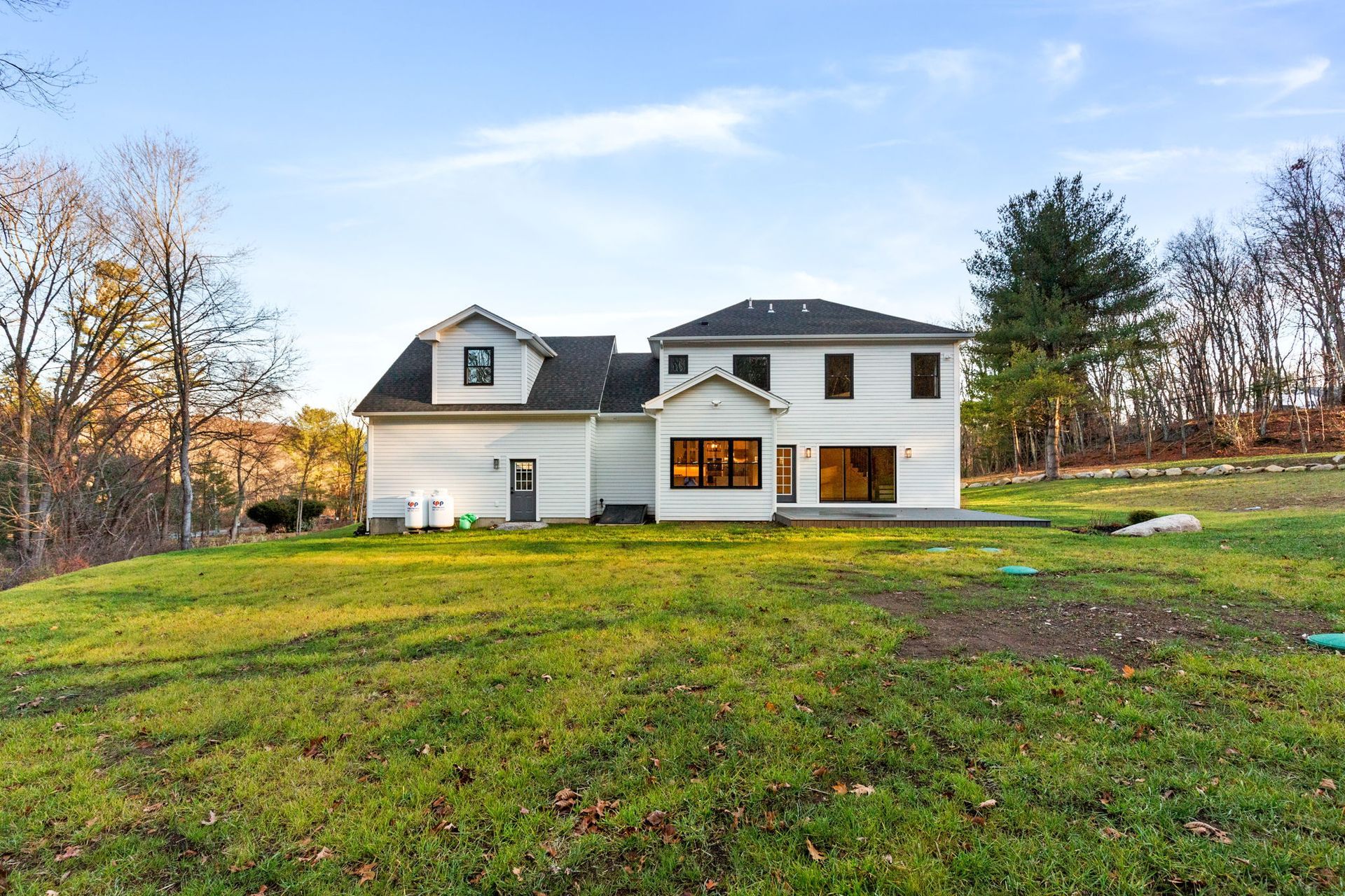 A large white house sits in the middle of a lush green field