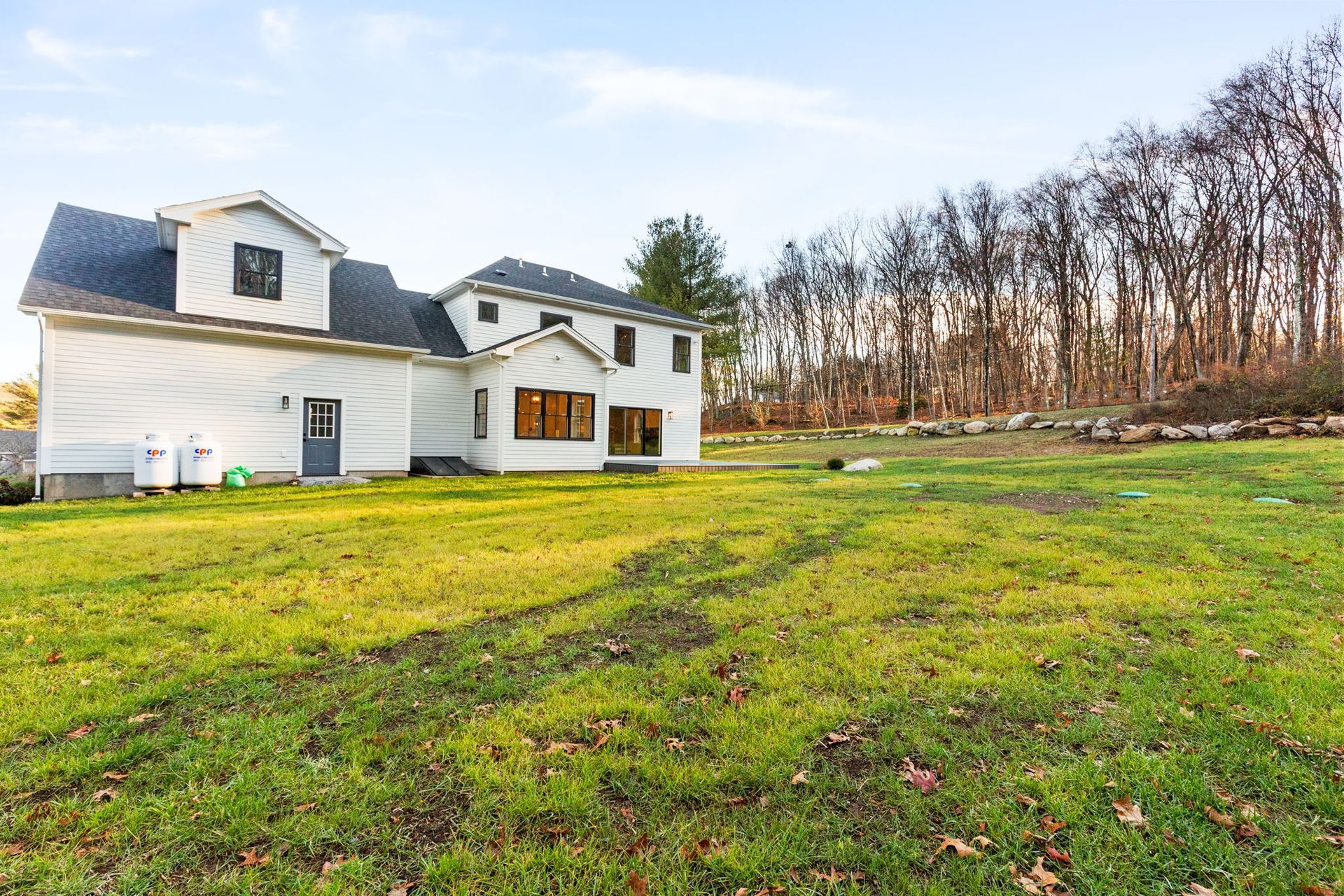 A large white house sits in the middle of a lush green field
