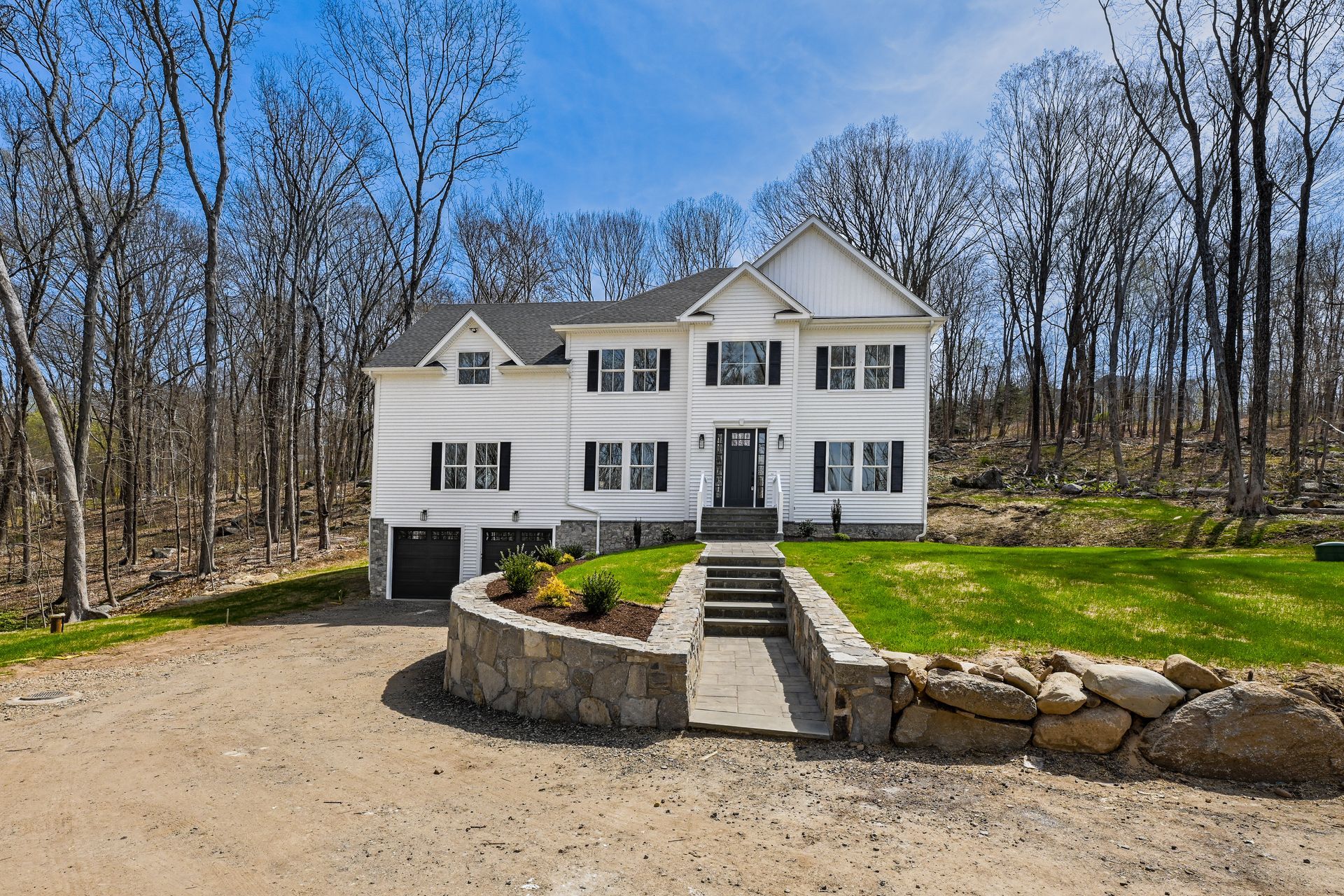 A large white house sits in the middle of a forest