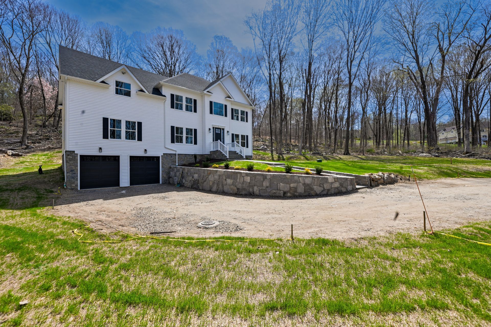 A large white house is sitting in the middle of a grassy field surrounded by trees.