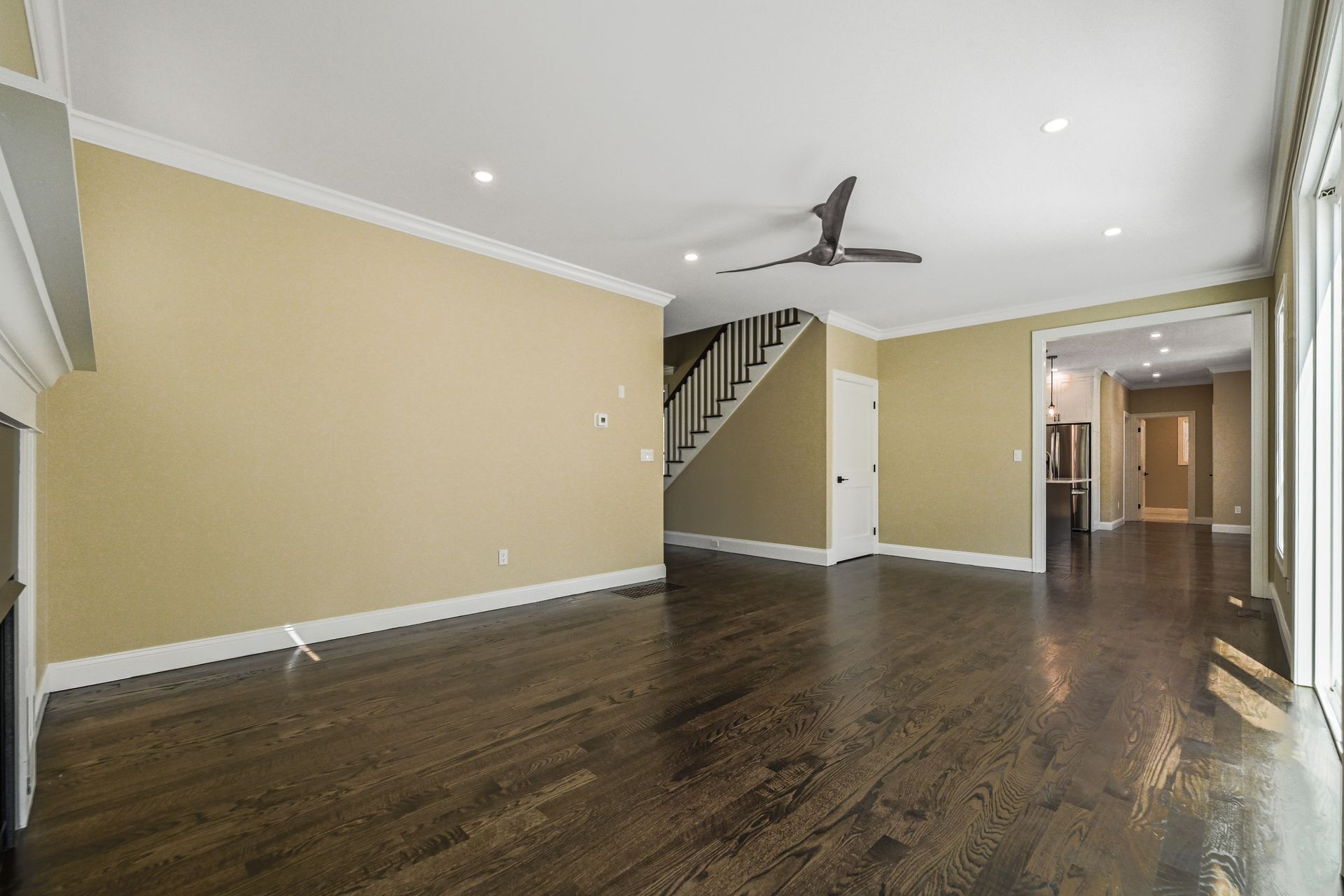 An empty living room with hardwood floors and a ceiling fan.