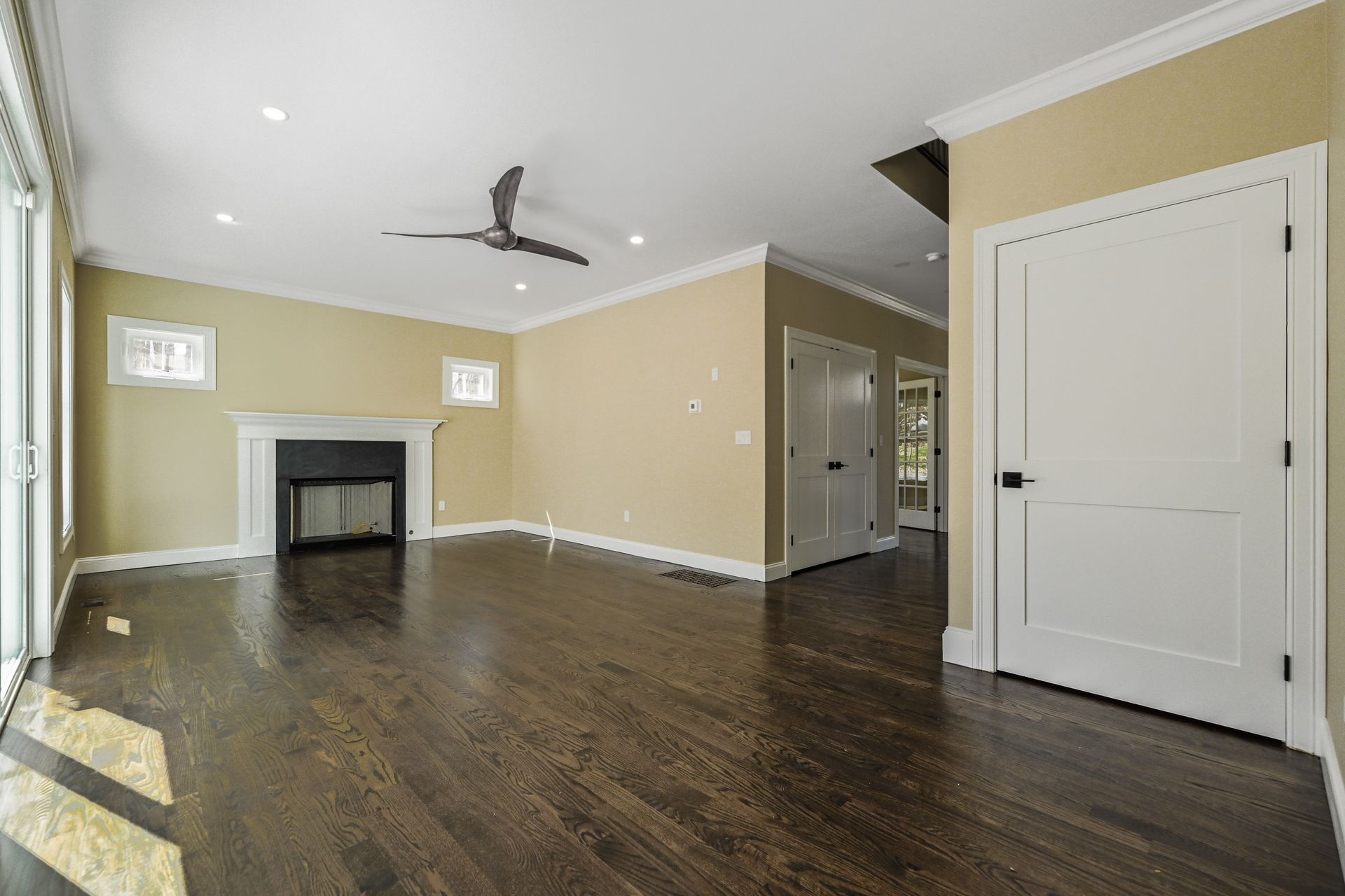 An empty living room with hardwood floors , a fireplace and a ceiling fan.