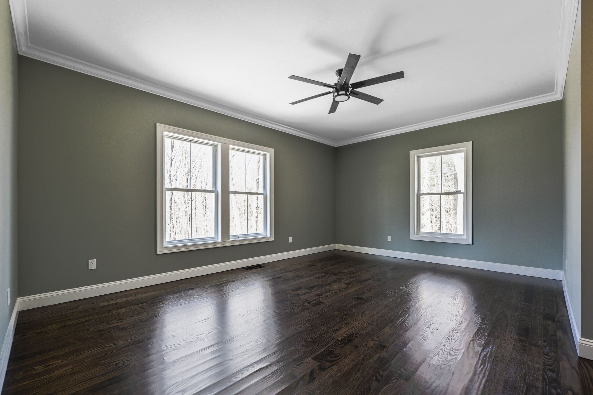 An empty living room with hardwood floors and a ceiling fan.