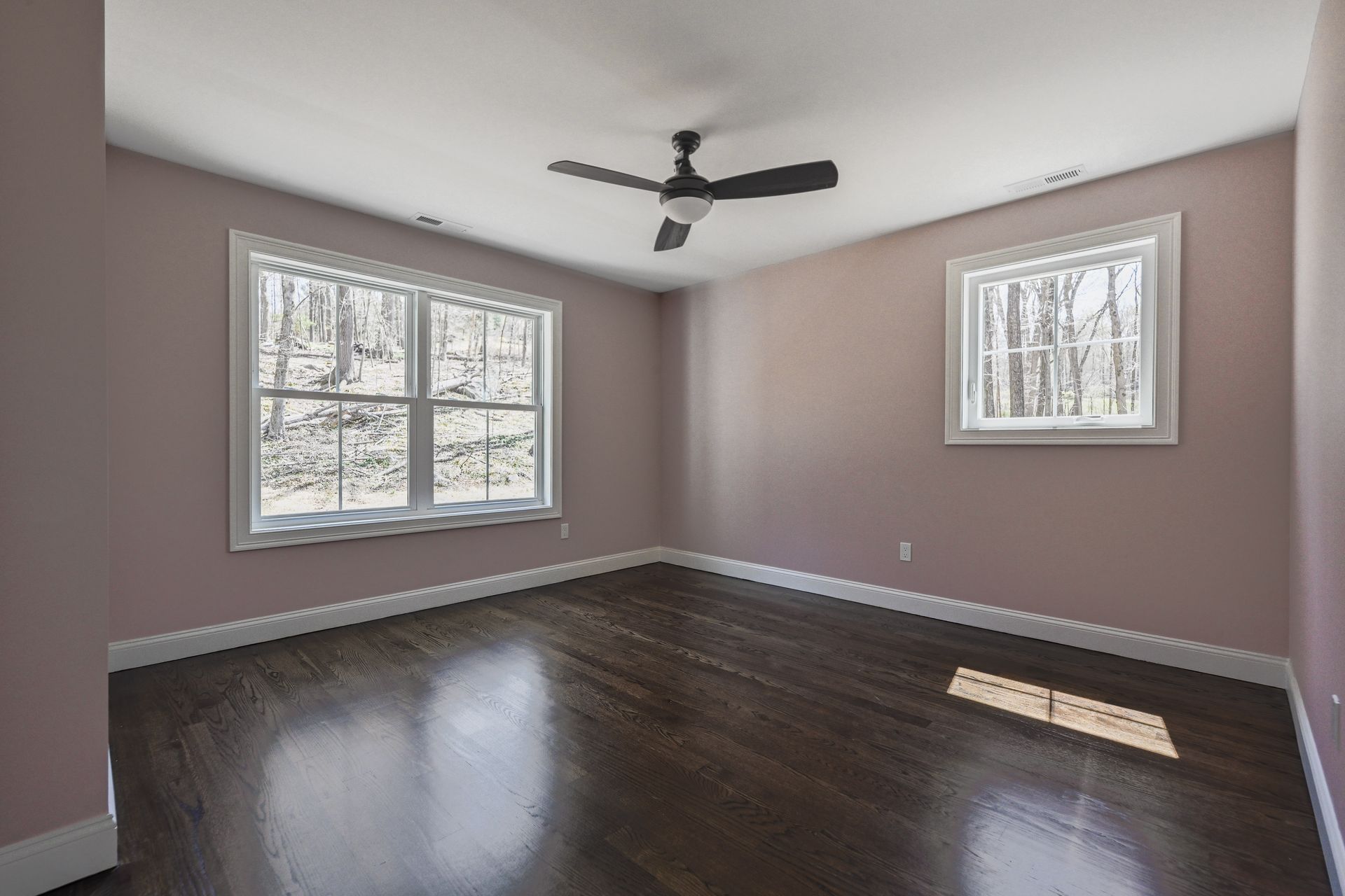 An empty room with hardwood floors and a ceiling fan.