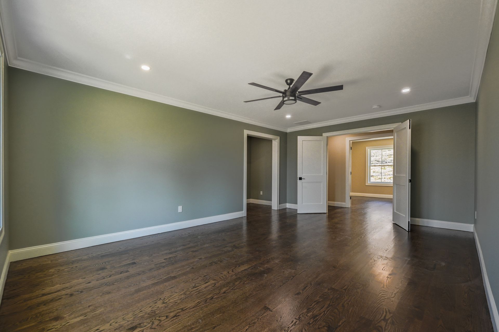 An empty living room with hardwood floors and a ceiling fan.