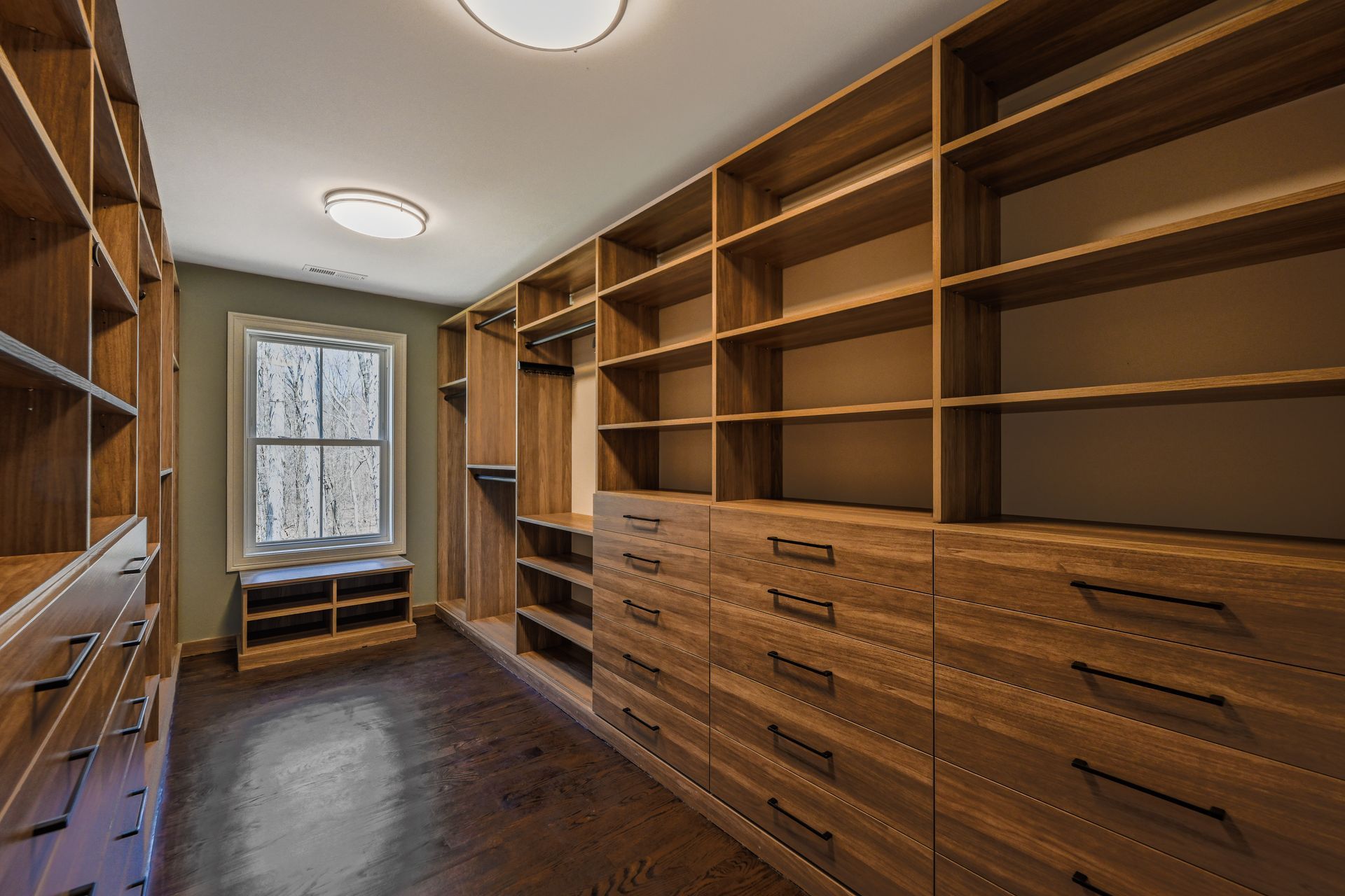 A walk in closet with lots of wooden shelves and drawers.