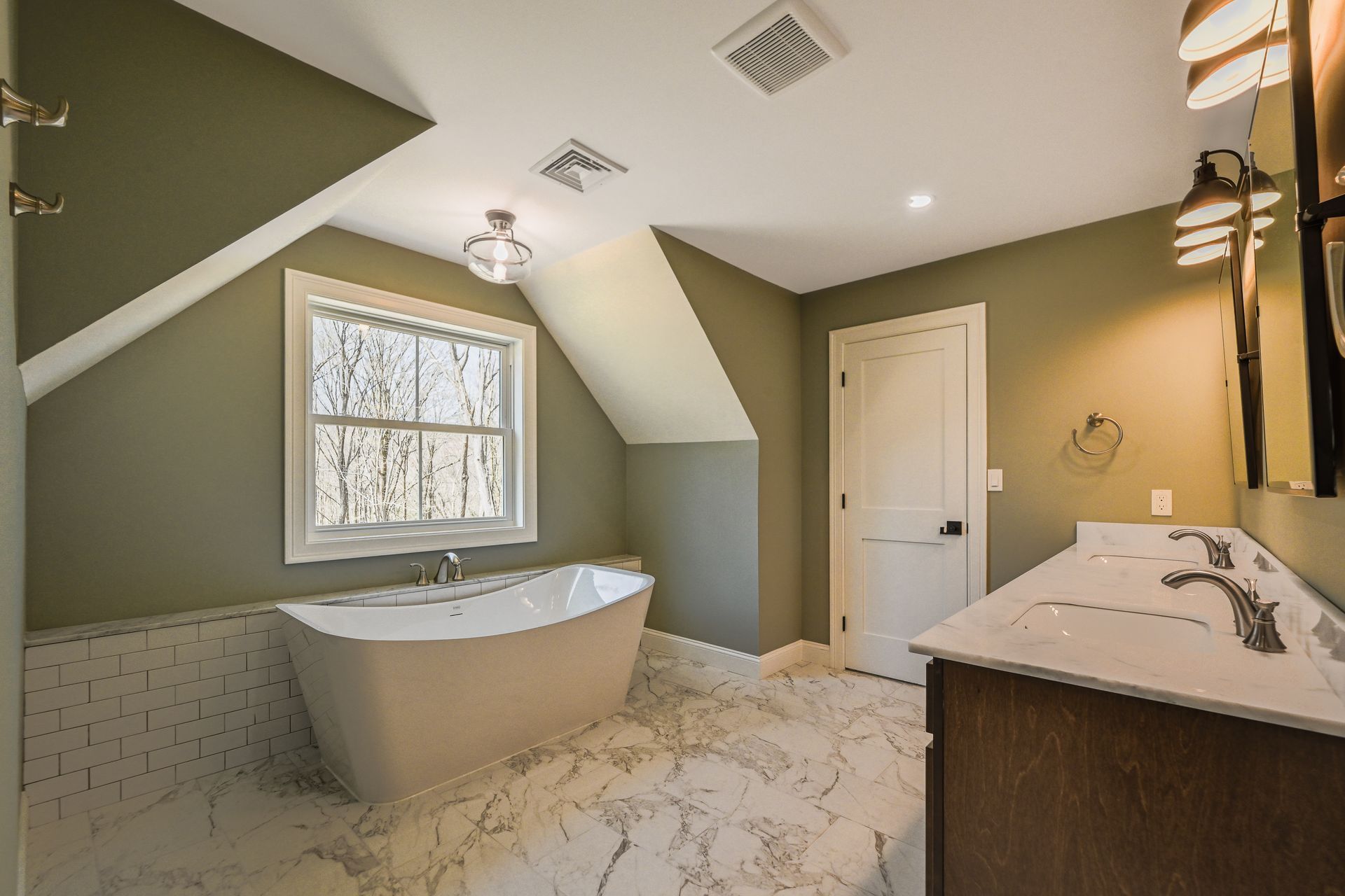 A bathroom with a bathtub , sink , mirror and window.