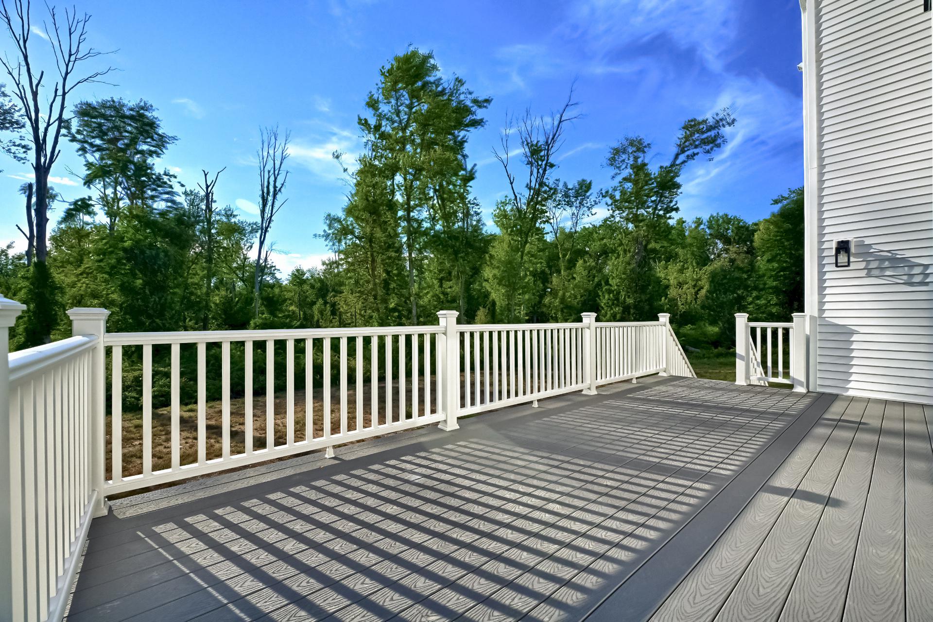A deck with a white railing and trees in the background