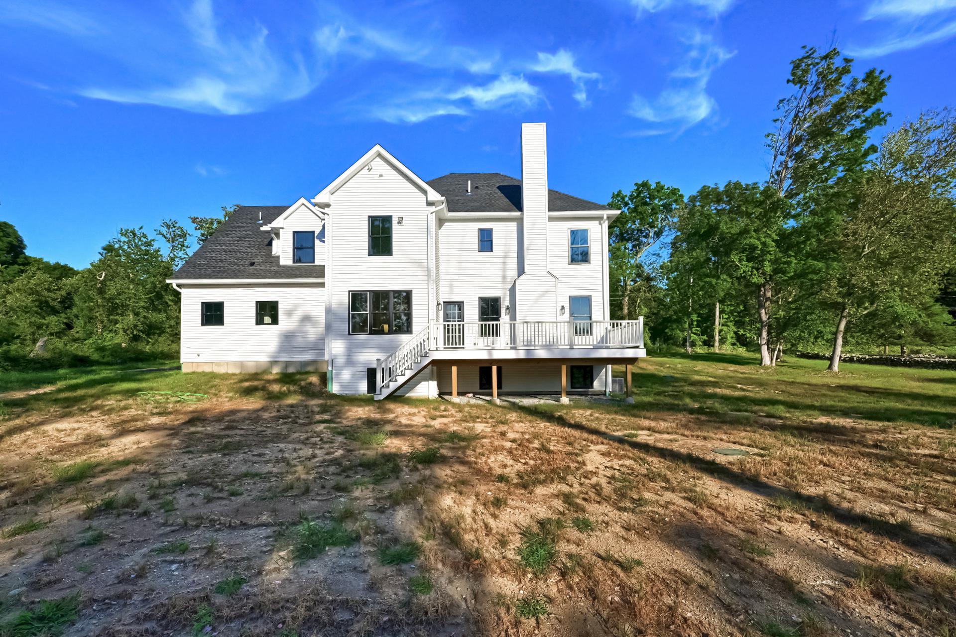 A large white house is sitting on top of a dirt field.