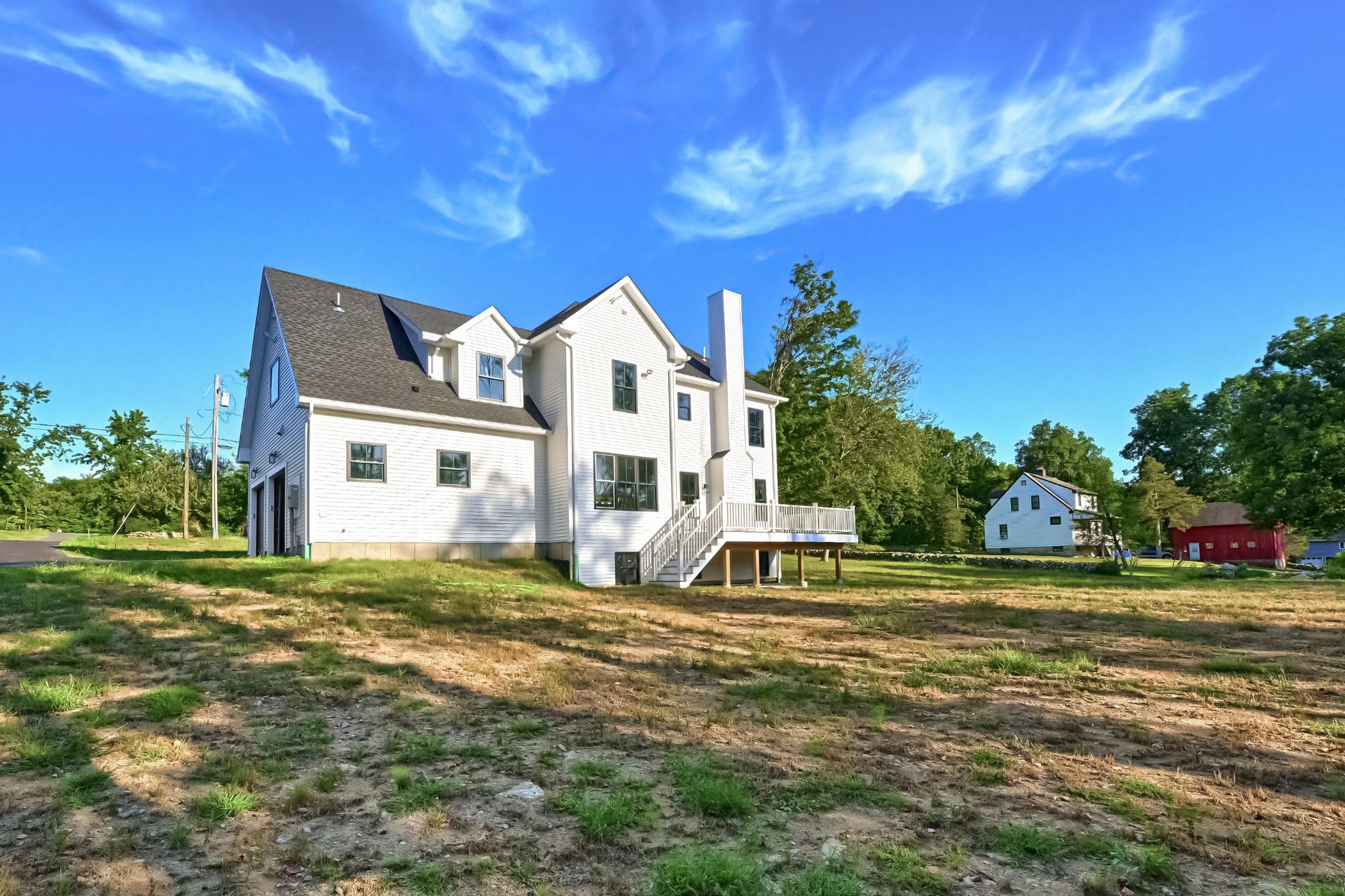 A large white house is sitting in the middle of a grassy field.