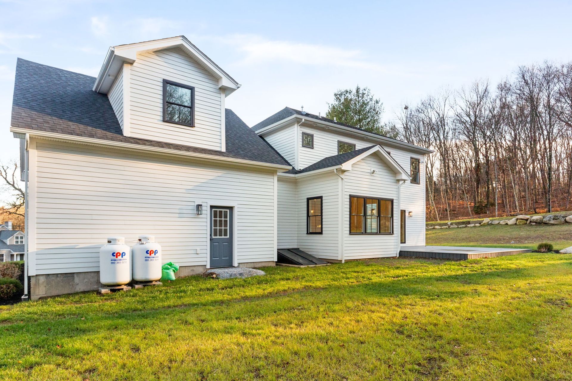 A white house with two propane tanks in front of it