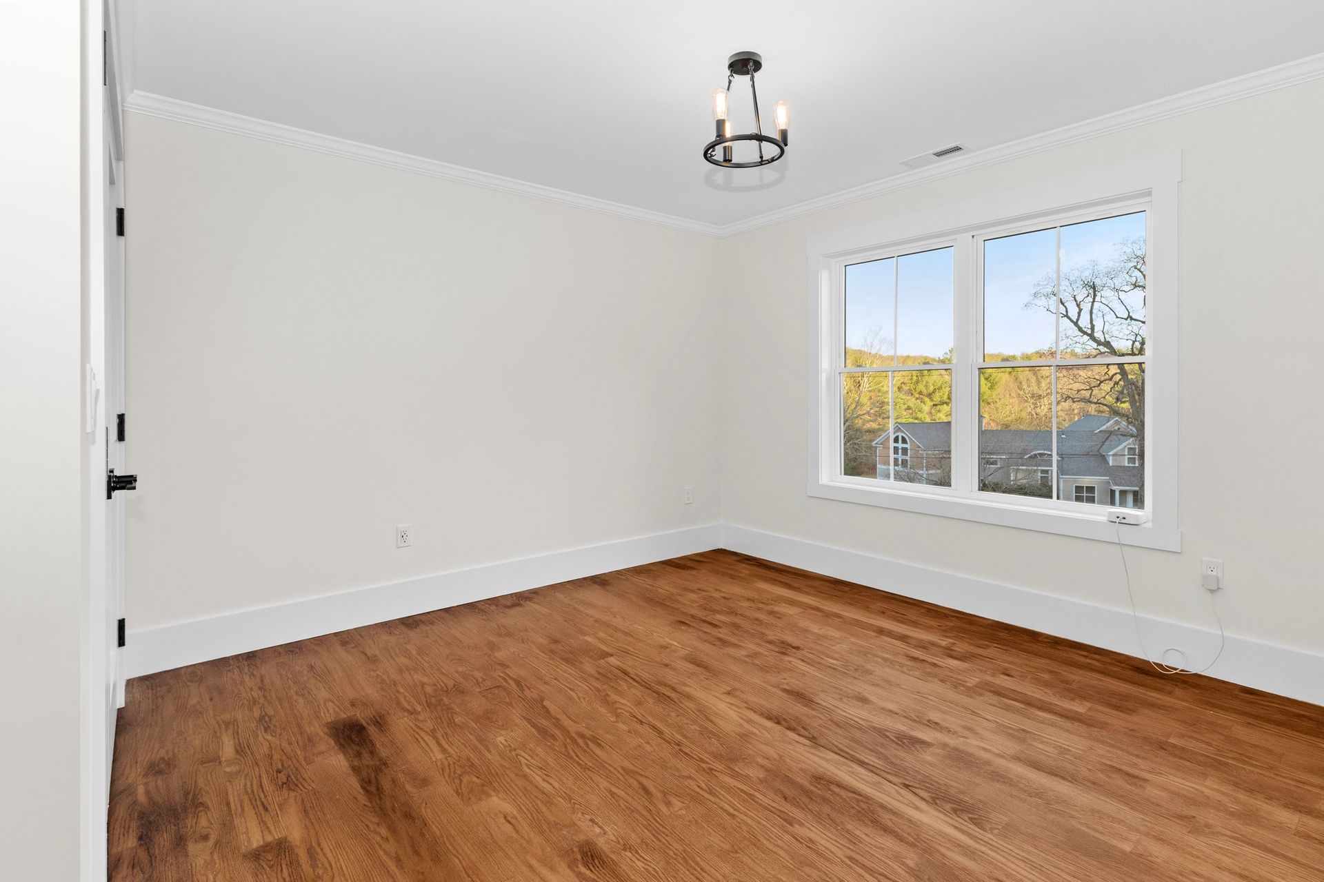 An empty room with hardwood floors and two windows