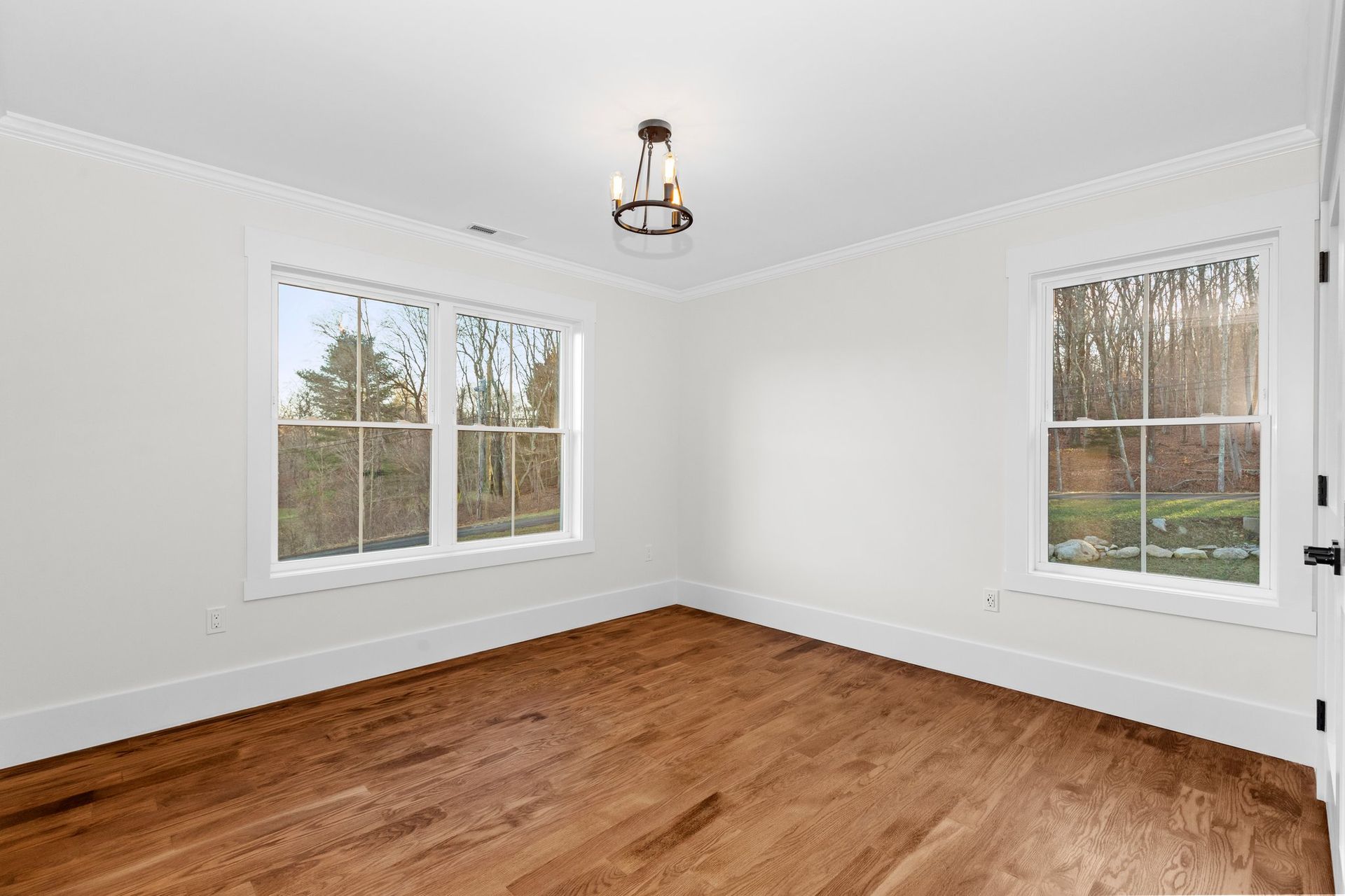 An empty room with hardwood floors and two windows