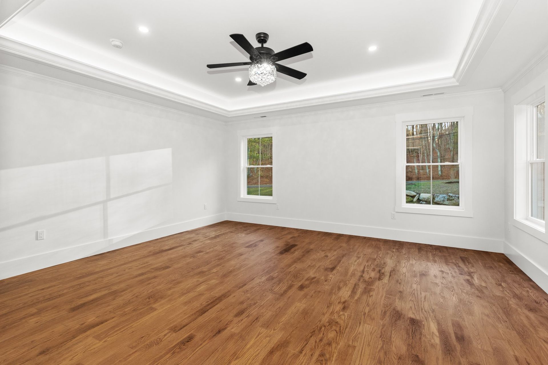 An empty room with hardwood floors and a ceiling fan