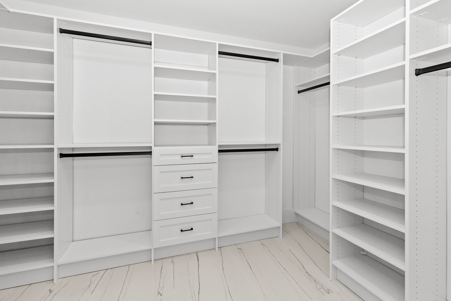 An empty walk in closet with lots of shelves and drawers.