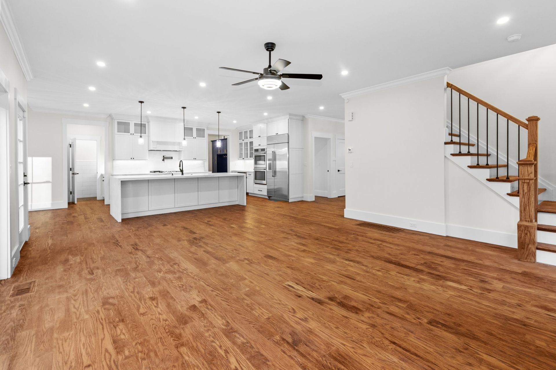 An empty kitchen with hardwood floors and stairs