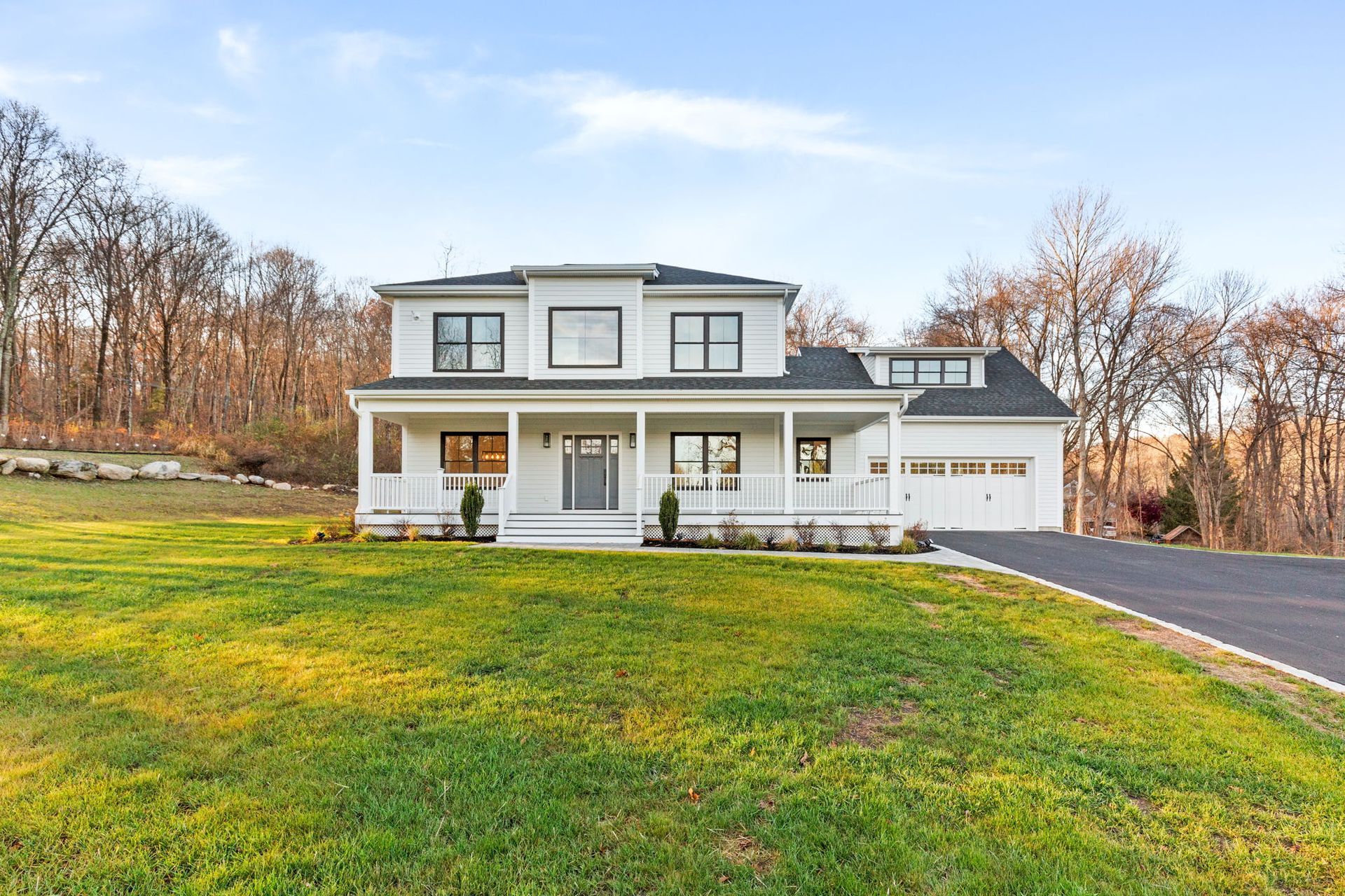 A large white house is sitting on top of a lush green hillside.