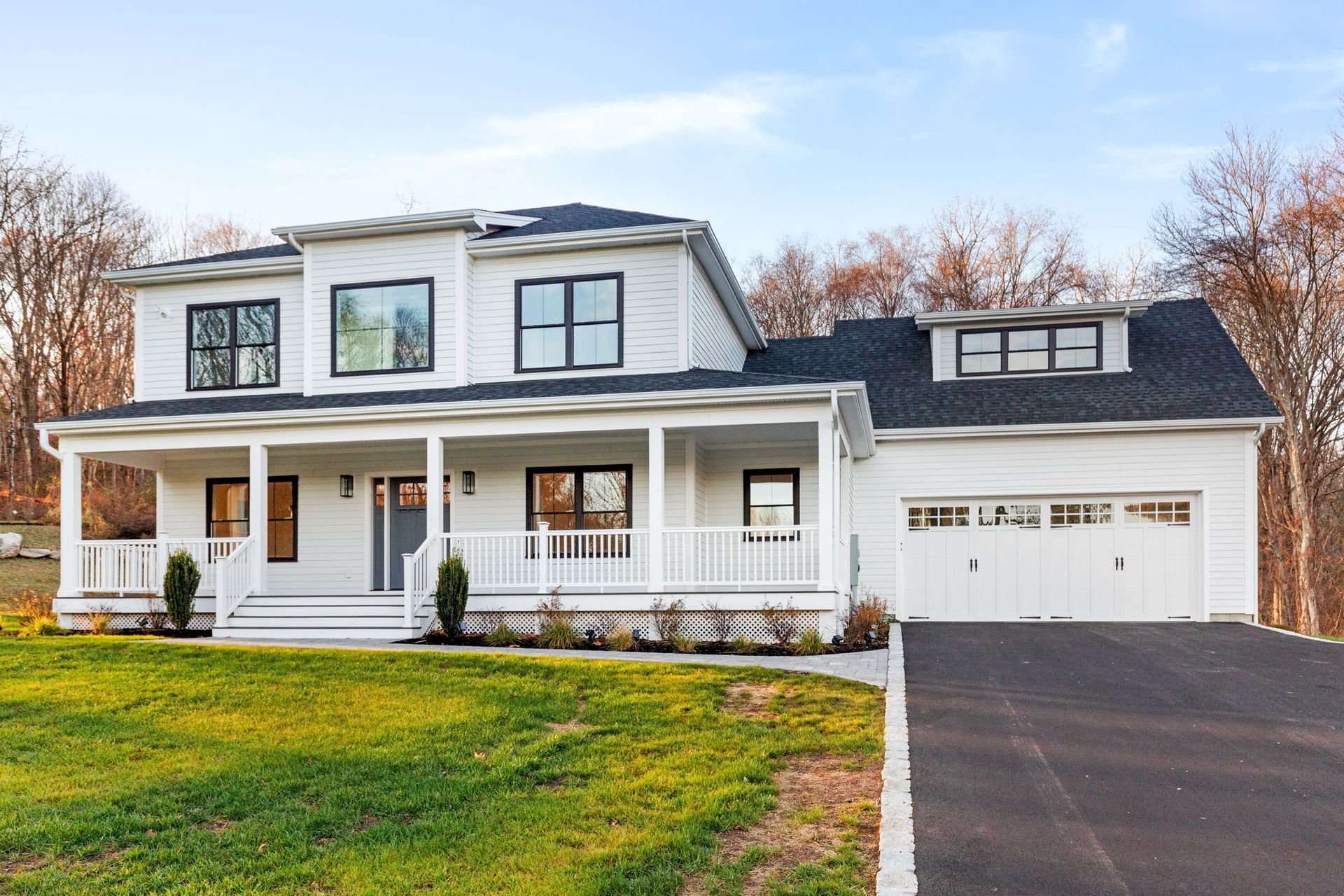 A white house with a black roof and a large porch