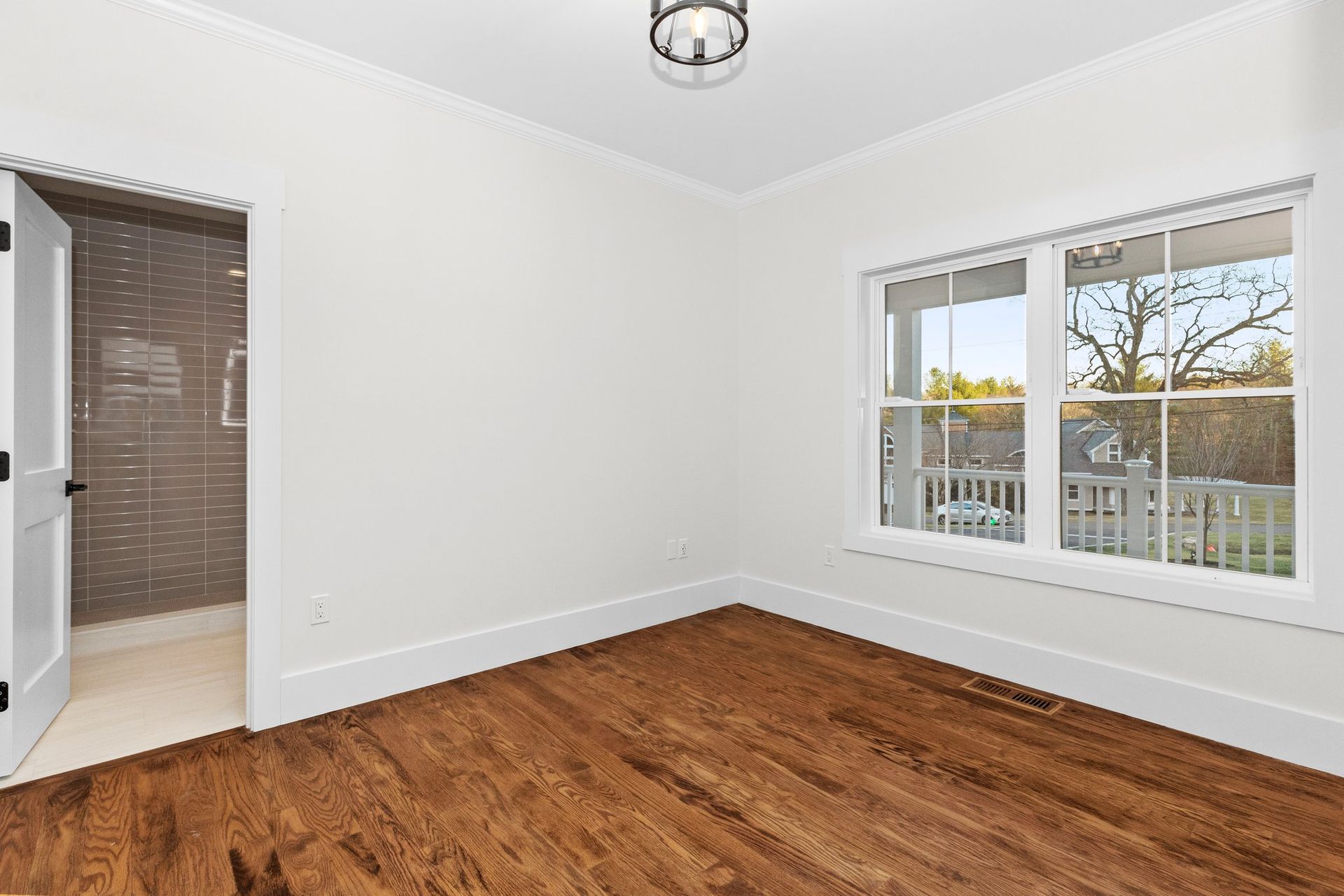 An empty room with hardwood floors and white walls