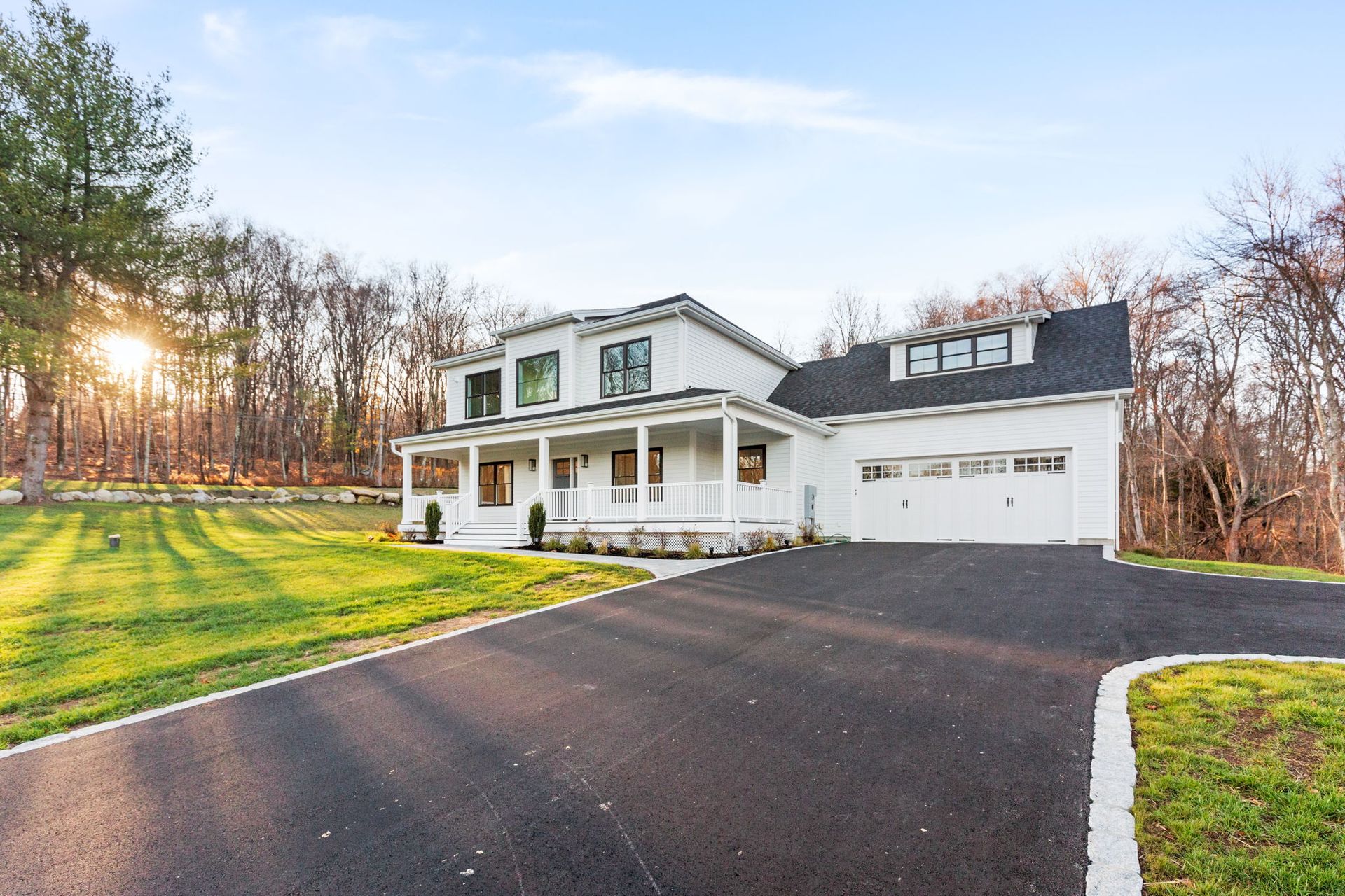 A white house with a black roof and a driveway
