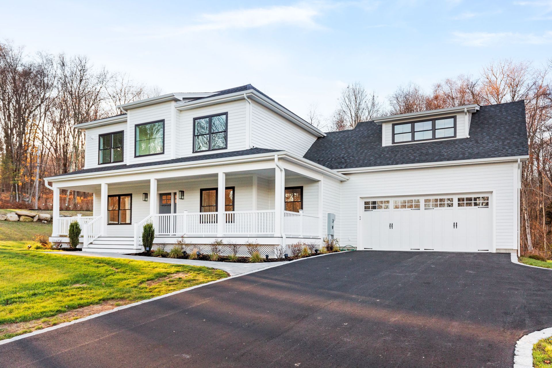 A white house with a black roof and a black driveway