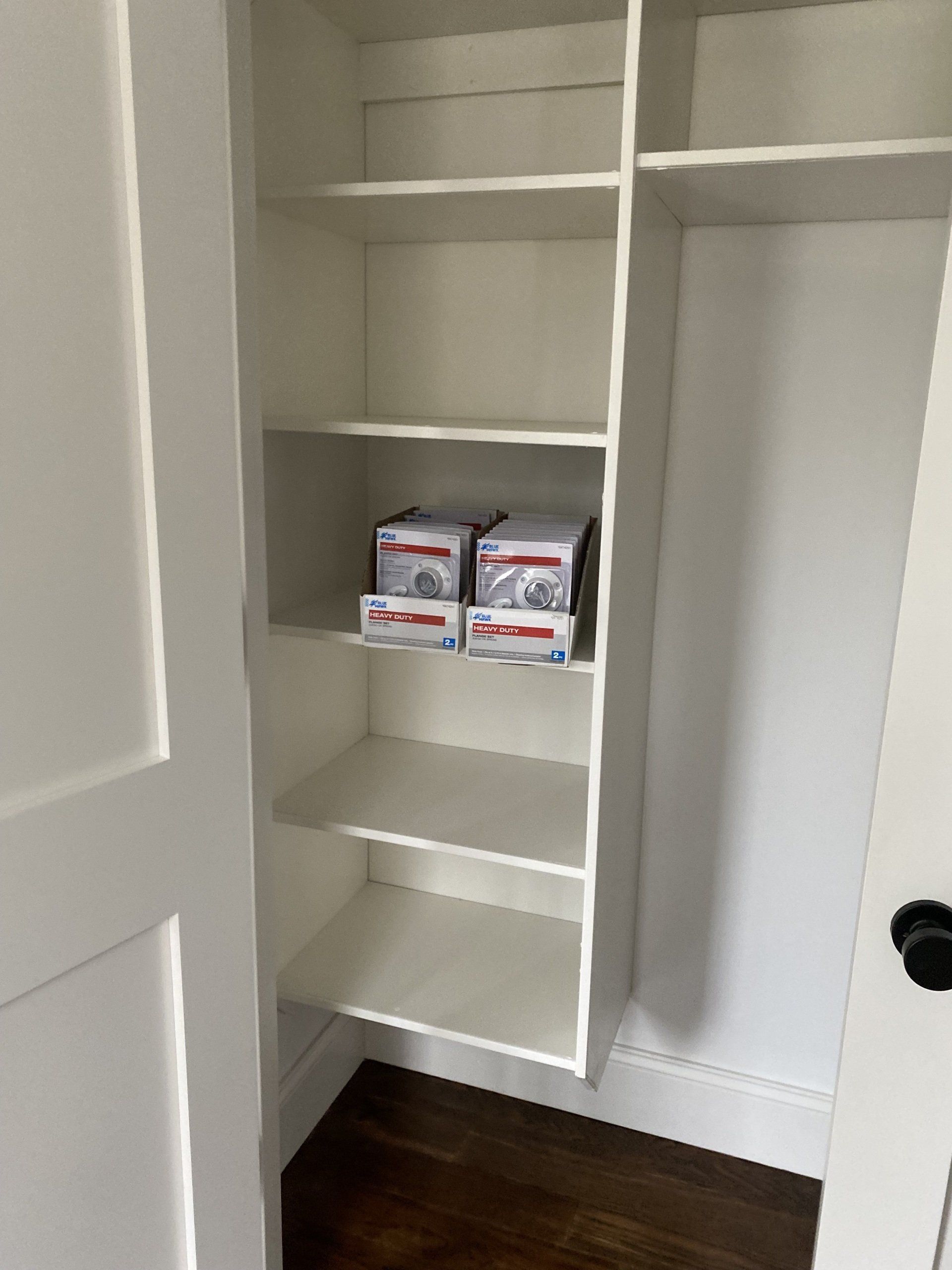 A closet with boxes on the shelves and a door.