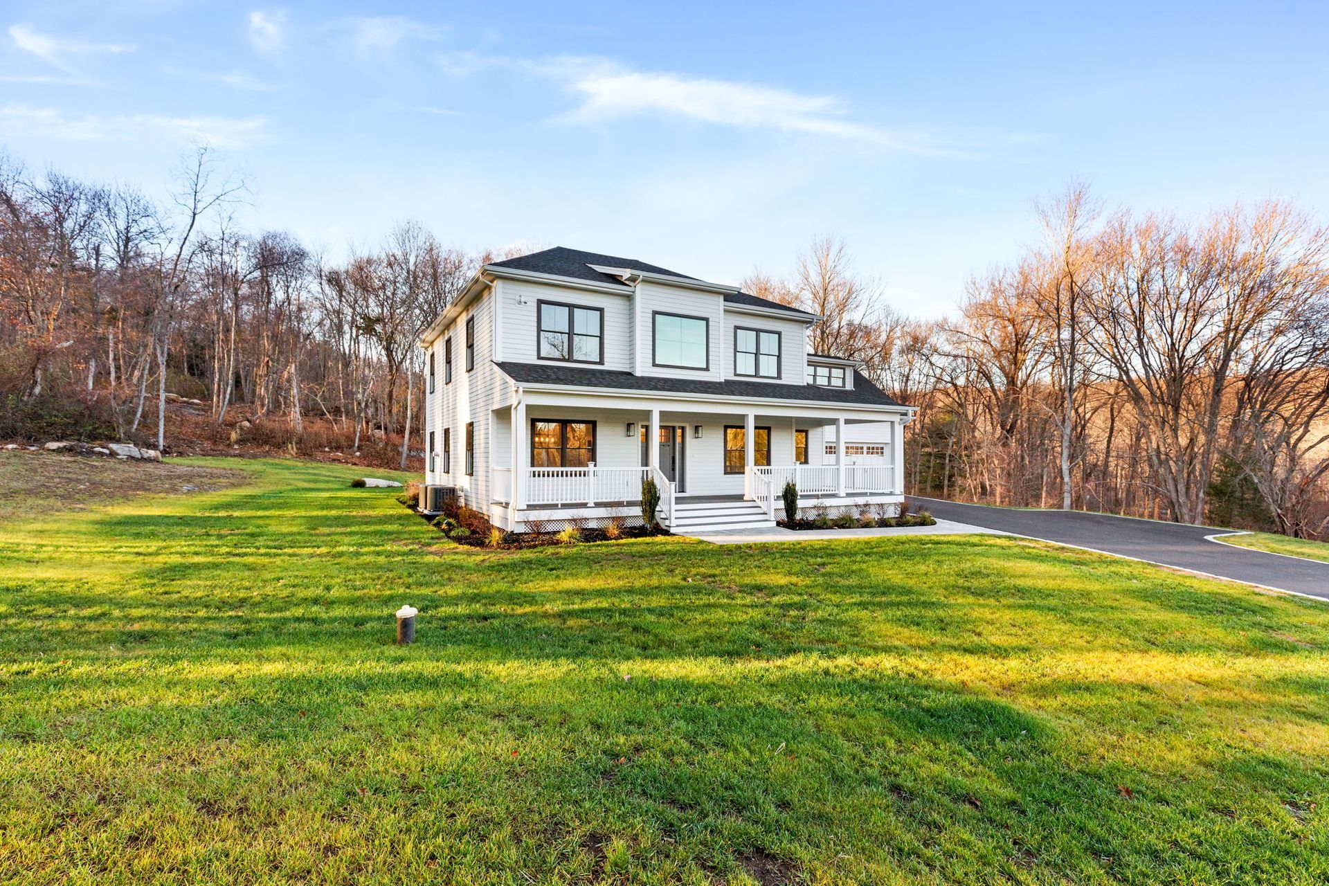 A large white house is sitting in the middle of a lush green field.
