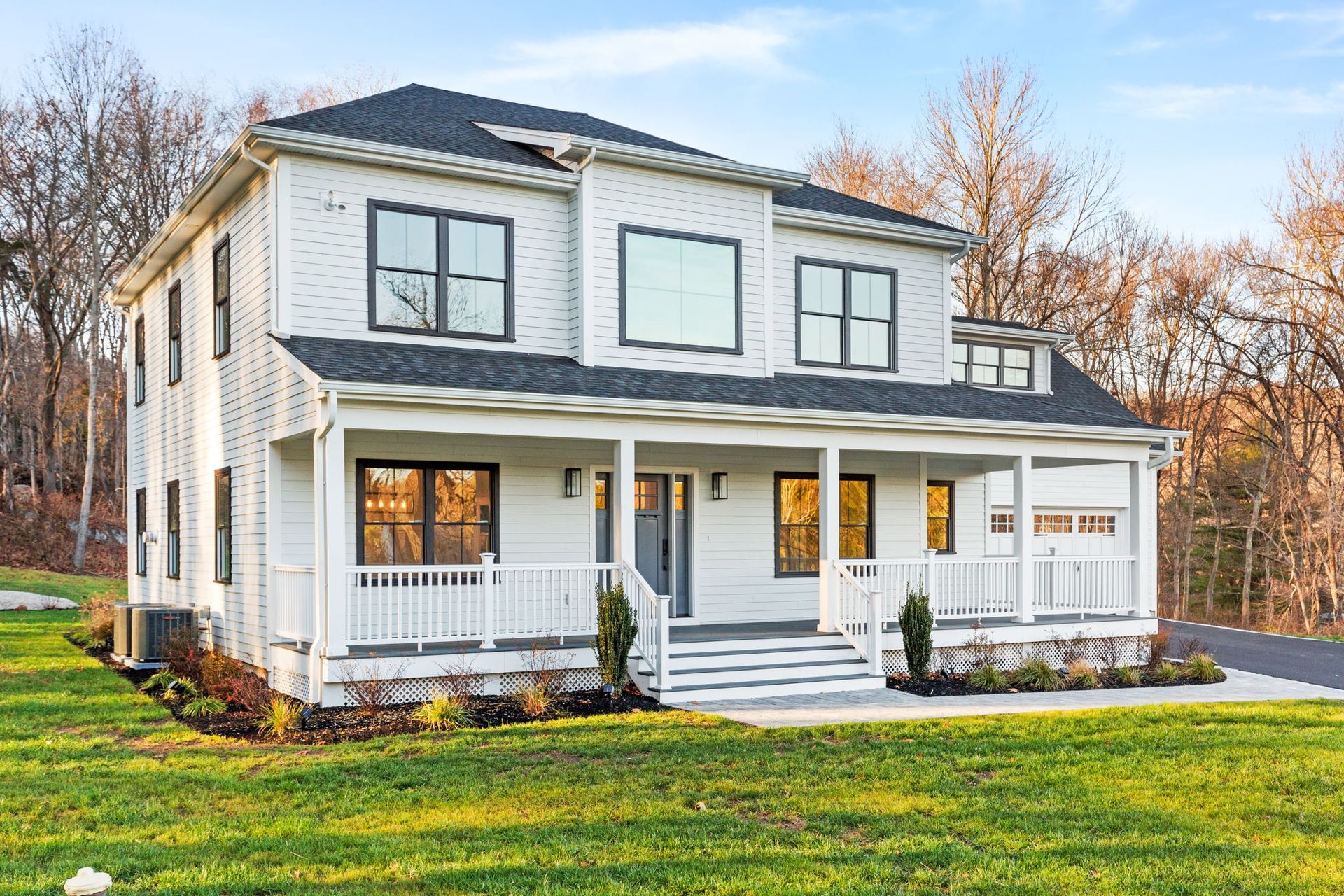 A white house with a black roof and a large porch