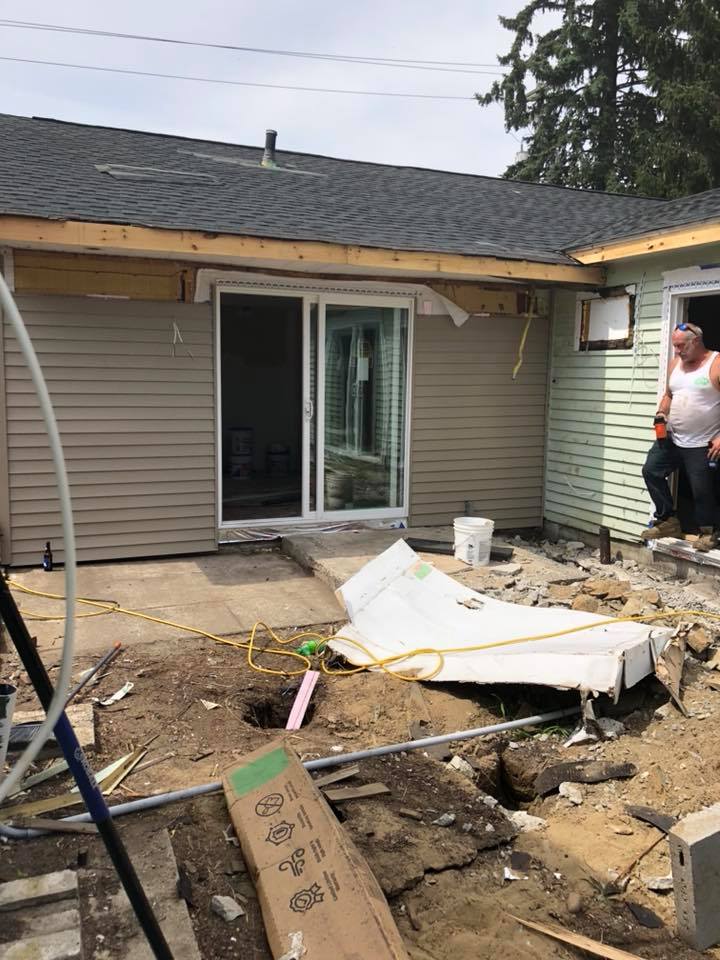 A man is standing in front of a house that is being remodeled.