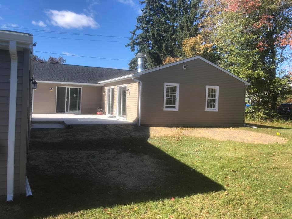 The back of a house with a large lawn in front of it.