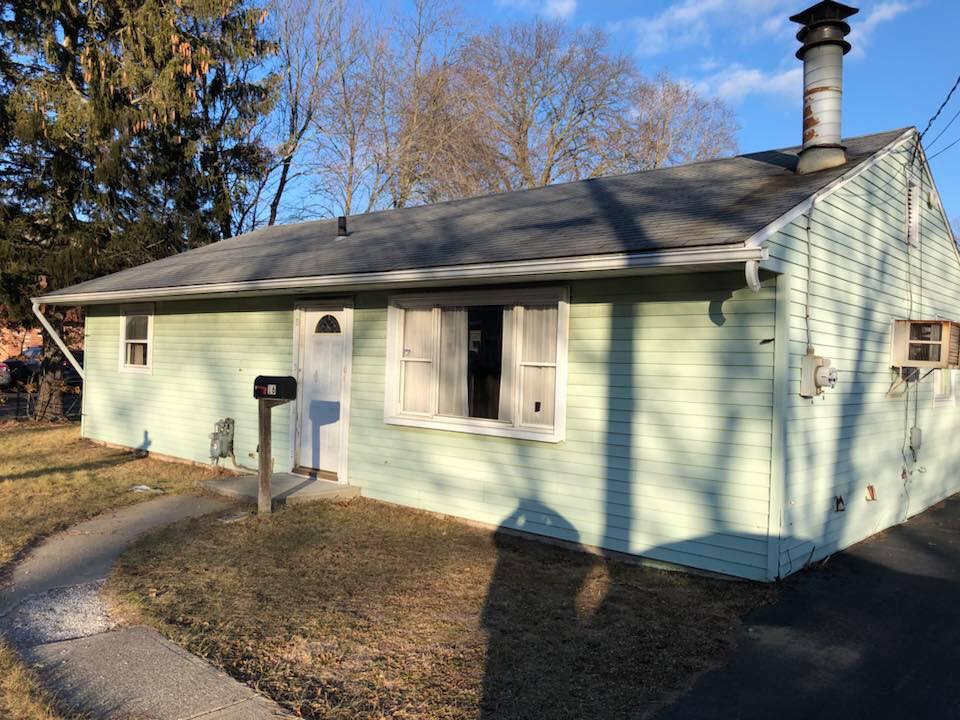 A small green house with a mailbox in front of it.