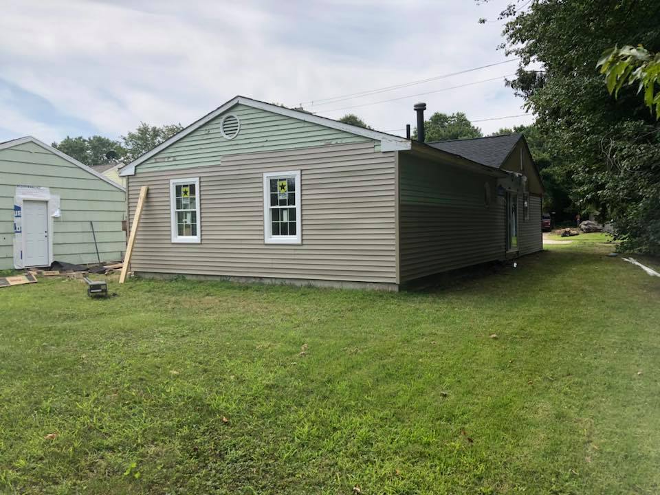 A house is sitting in the middle of a lush green field.