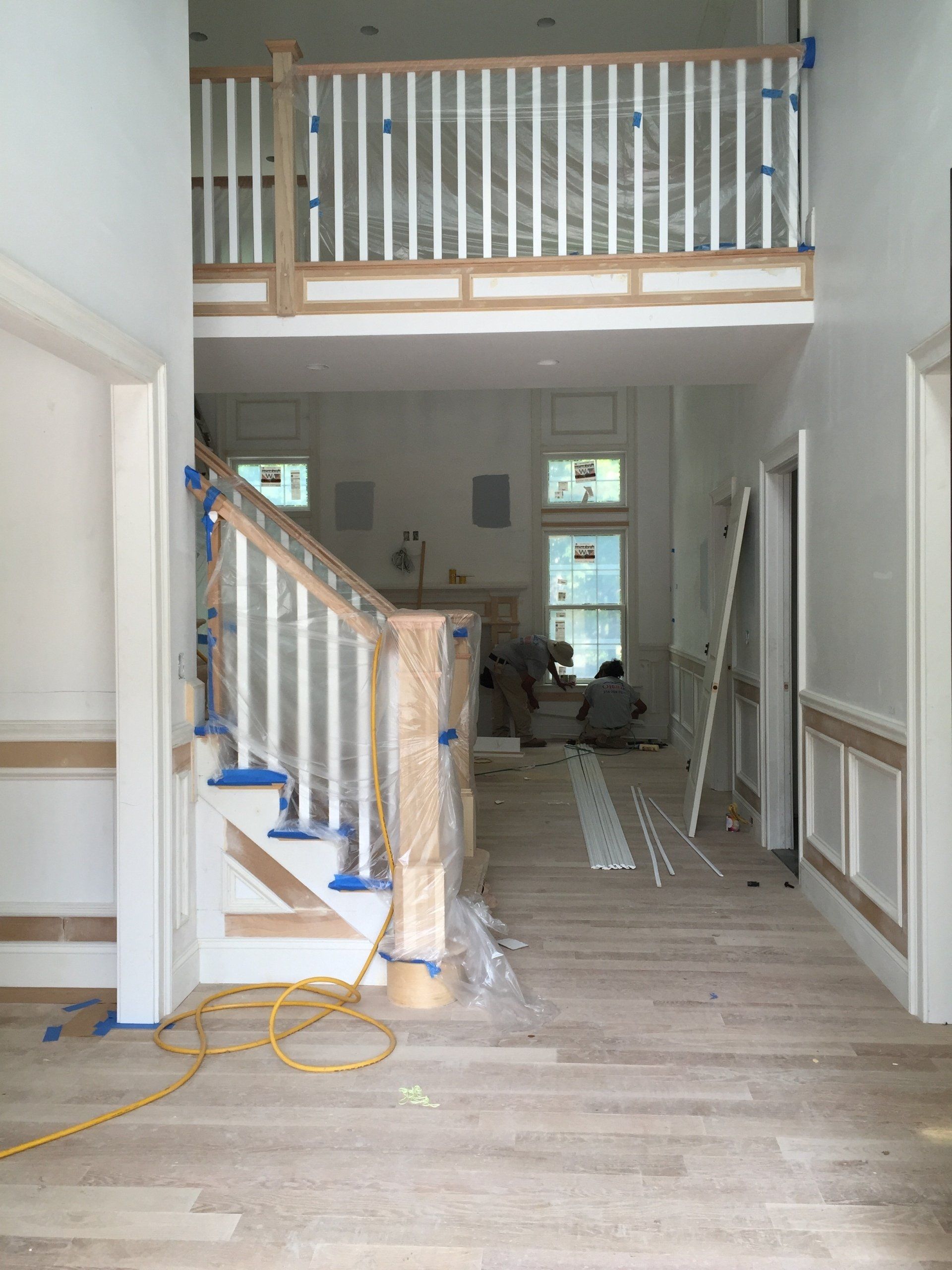 A hallway with stairs and a balcony in a house under construction