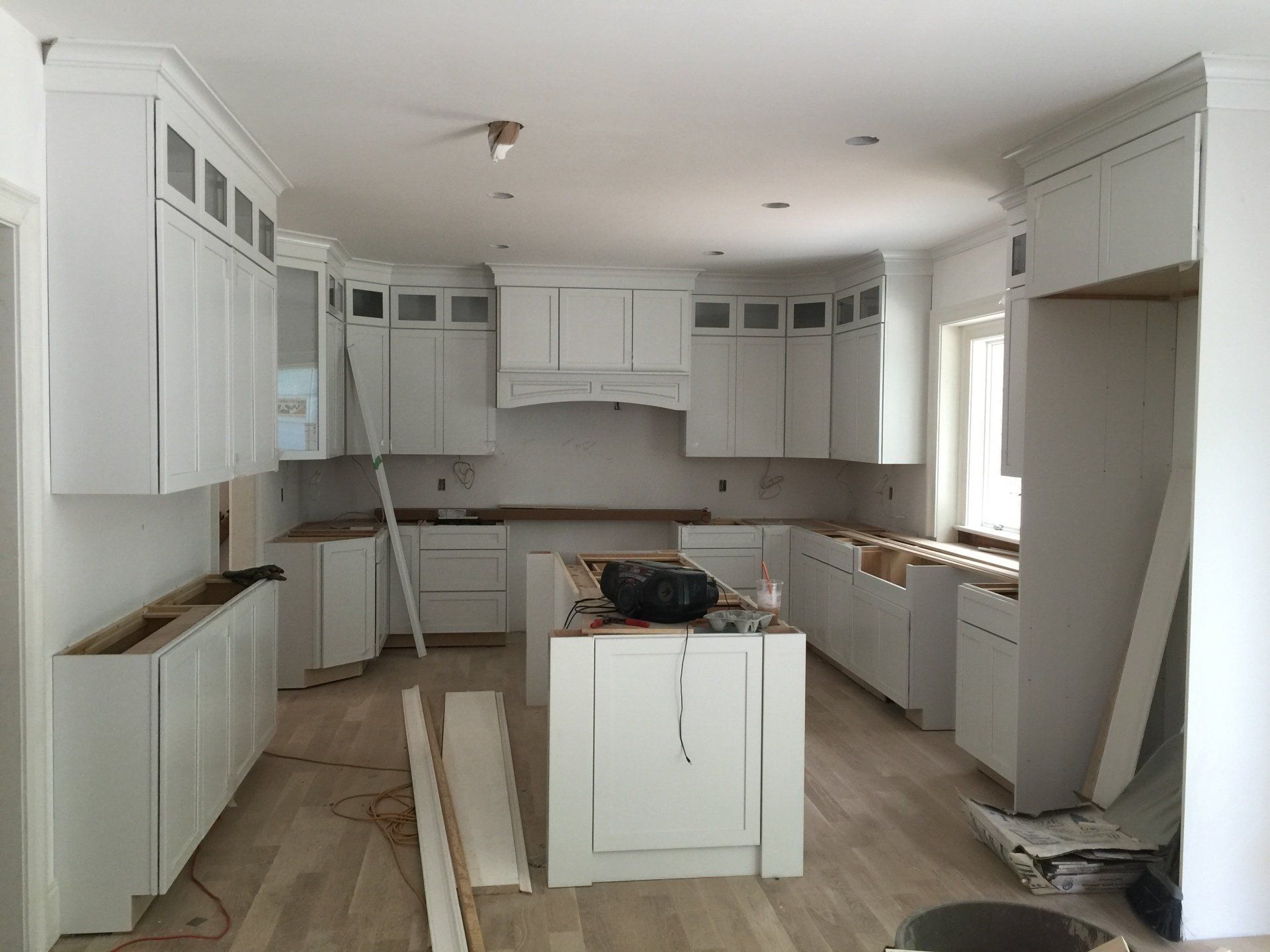 A kitchen under construction with white cabinets and a large island.