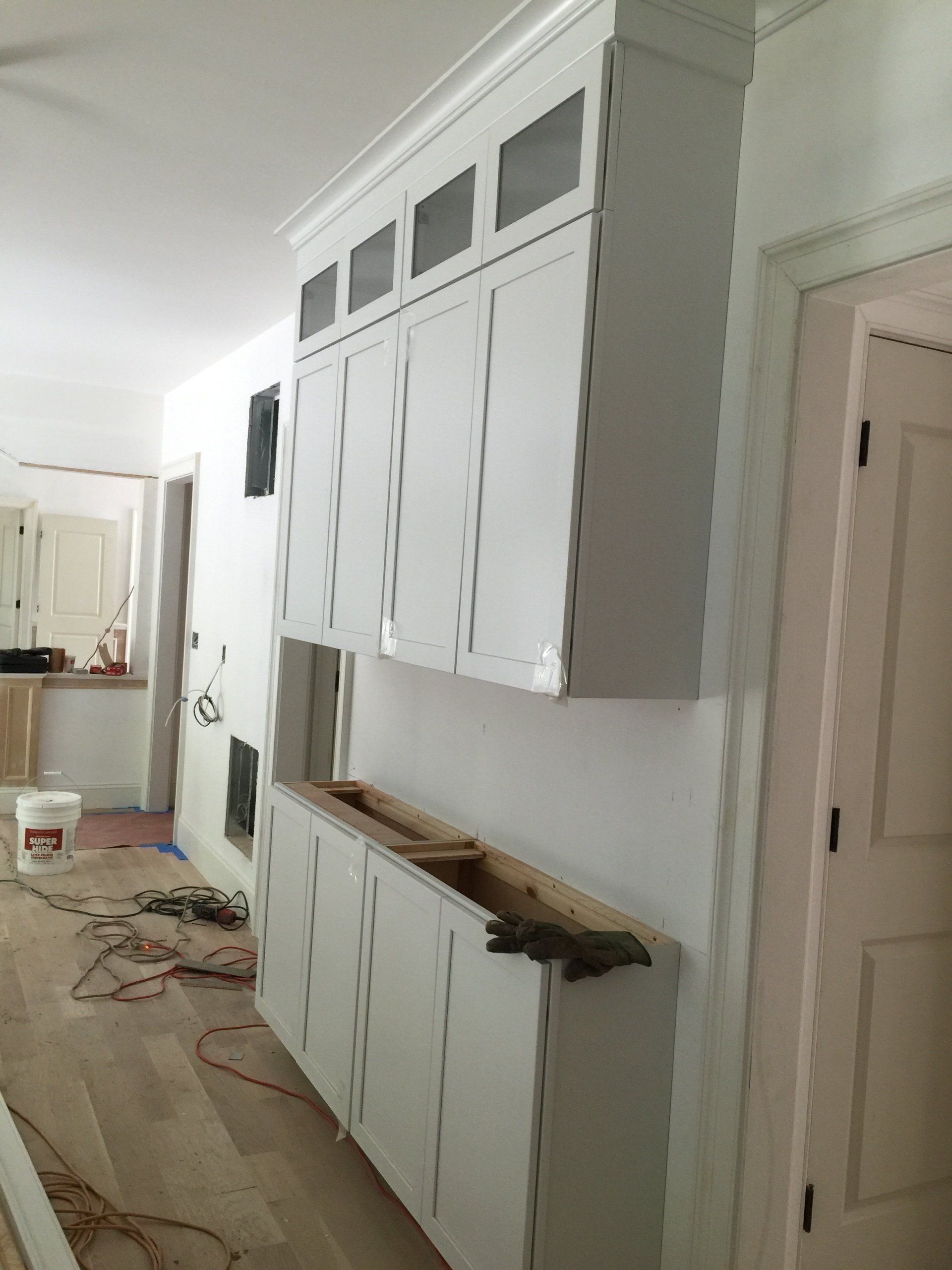 A kitchen with white cabinets and a bucket of paint on the floor