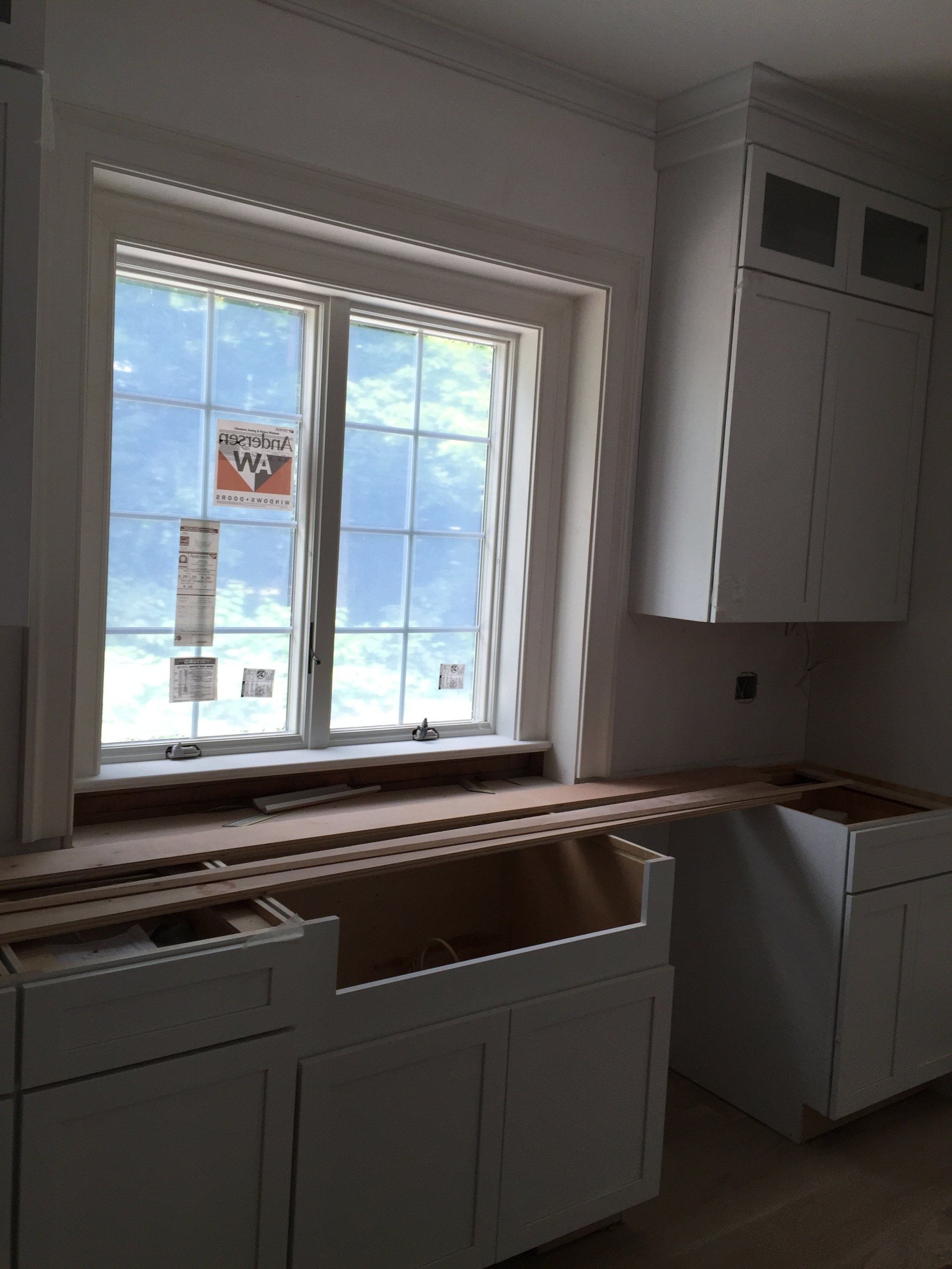 A kitchen with white cabinets and a large window