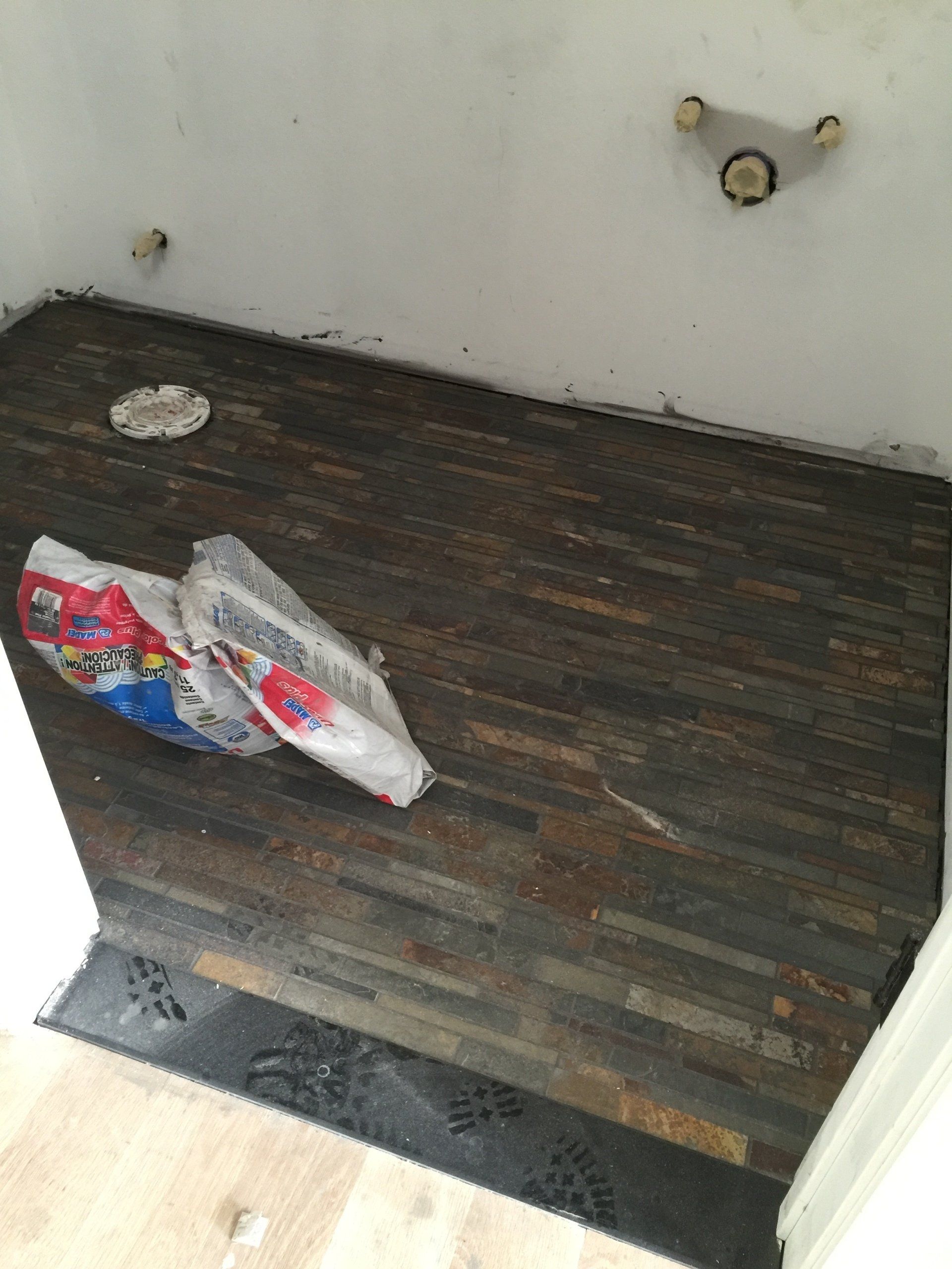 A bag of toilet paper is laying on the floor of a bathroom.